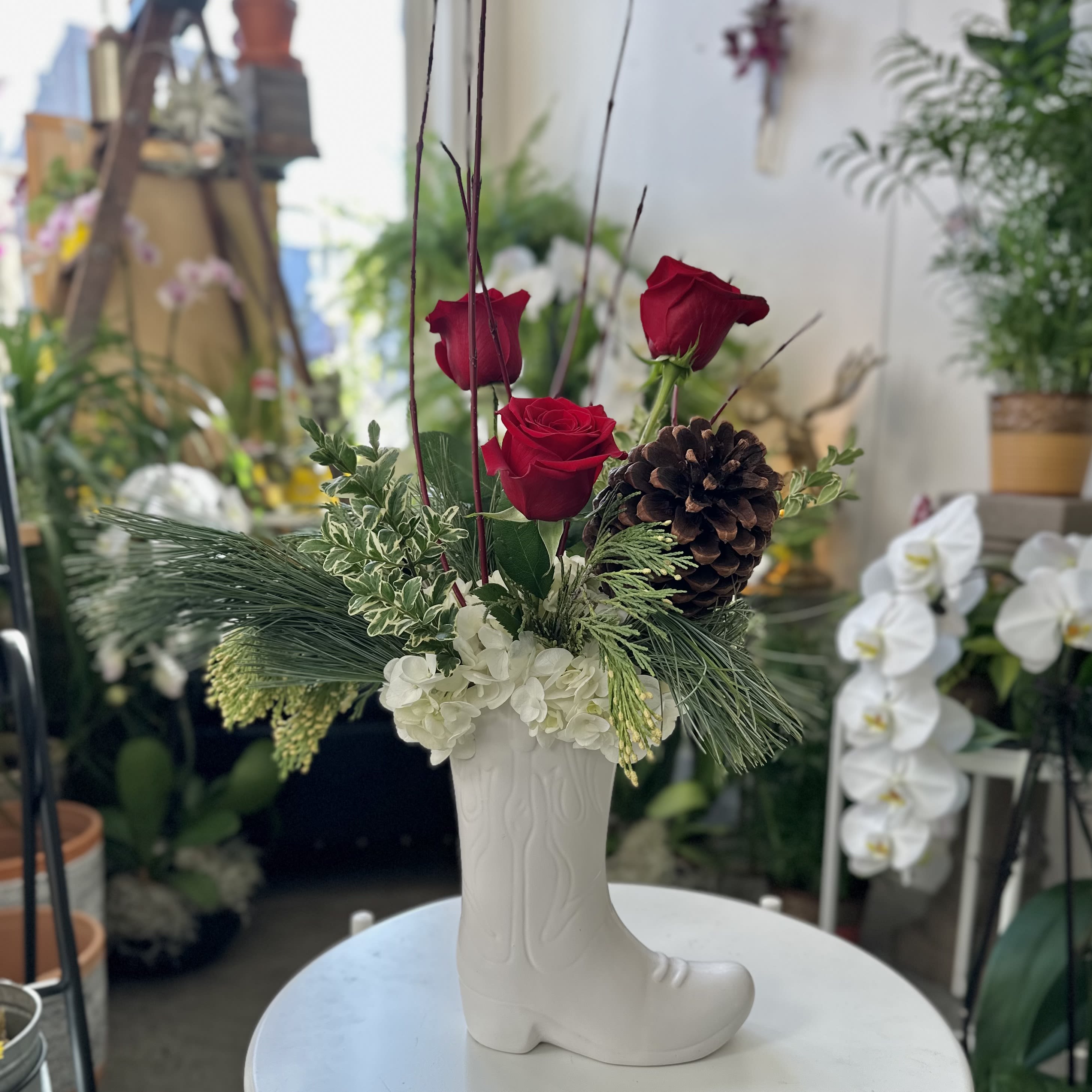 Kickin' Country Christmas - Lush evergreens, hydrangea and red twig dogwood fill this cowboy boot, and red roses and a Jeffrey pine cone kick off the holidays, country style.