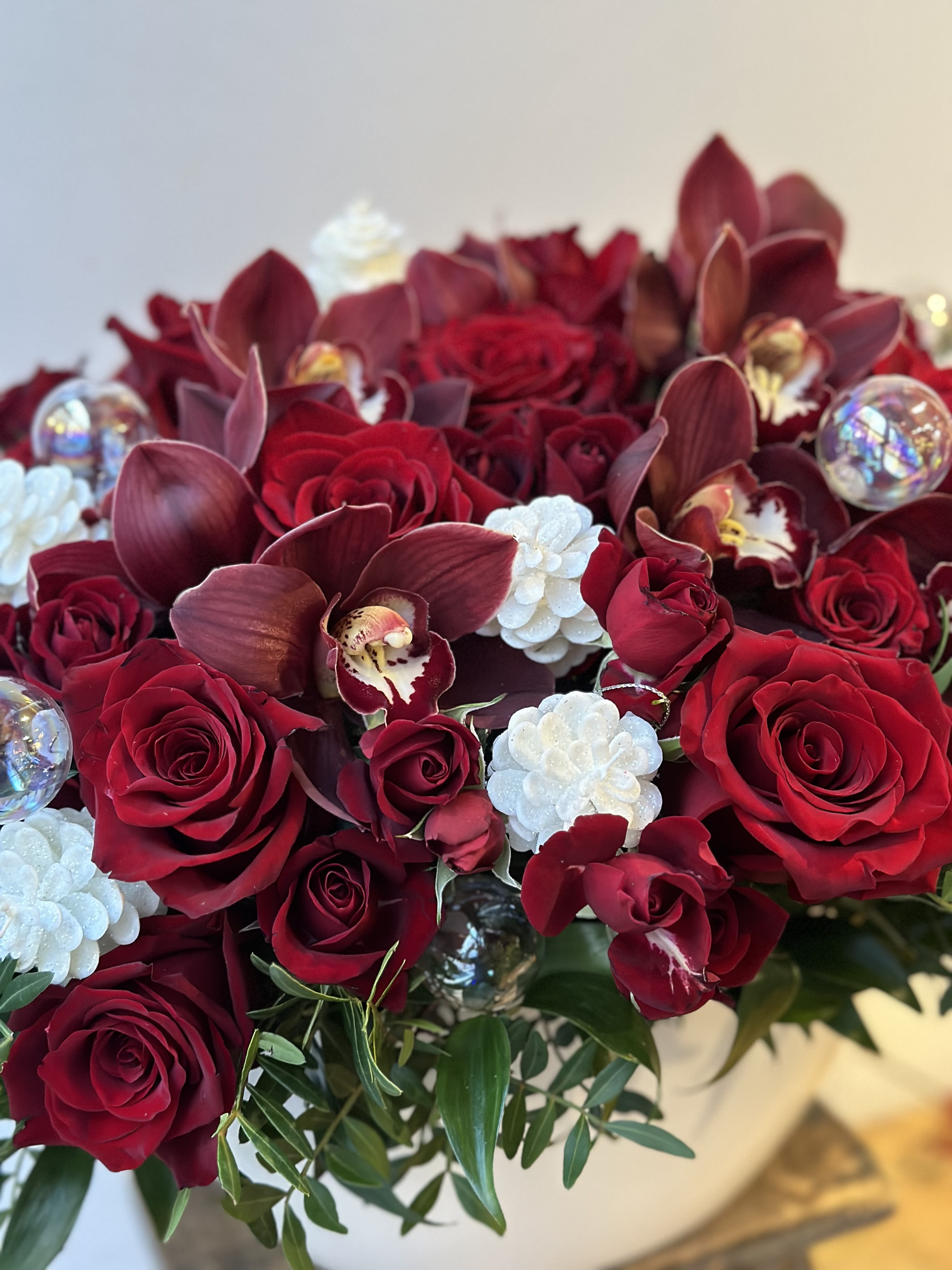 Sleigh bell ring  - Embrace the spirit of the holidays with the captivating Sleigh Bell Ring. Nestled in a long white ceramic vase overflowing with lush red roses Accented with shimmering white holiday ornaments Creates a cozy, festive ambiance in any space The soothing, ringing sound of the sleigh bell transports you to a winter wonderland, evoking cherished memories of the season. Paired with the luxurious red roses and sparkling ornaments, this piece radiates holiday elegance and charm.  Display the Sleigh Bell Ring as the centerpiece of your holiday decor to instantly transform any room. This versatile, eye-catching design makes a thoughtful, meaningful gift for anyone who loves to celebrate the magic of the holidays in style. Bring the enchantment of the season home with the Sleigh Bell Ring.  We offer same day flower delivery in Manhattan, Queens, Bronx, Brooklyn, Staten Island and West Chester counties. We have the prettiest and most luxurious flowers to choose from and our designs are unique and whimsical. We carry Peonies almost every day of the year!! Best florist, nyc, local florist, send flowers, flower delivery, same day delivery, florist around me, flower shop, best flower shop, flowers, flower delivery, peony, peonies, same day flower delivery, wedding florist, best florist nyc, nyc florist, florist near me, manhattan florist, brooklyn florist