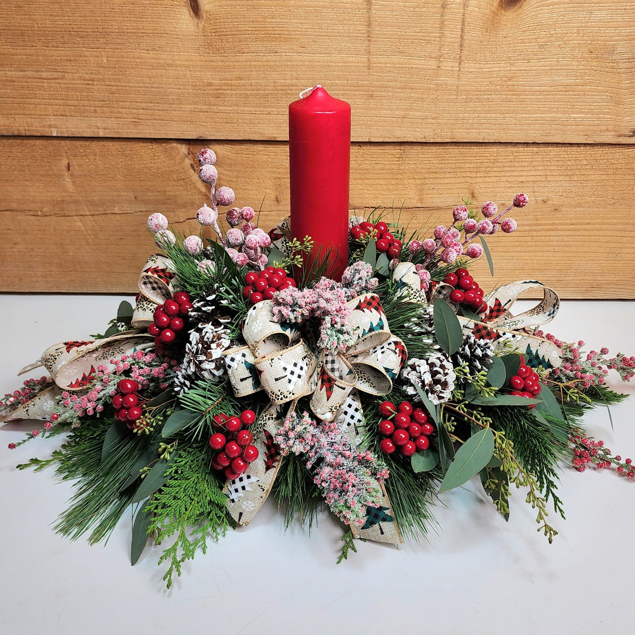 Winter Warmth - Winter Warmth combines stunning blooms and lovely candle light into one amazing package! Featuring a red pillar candle, this centerpiece also comes with faux frosted berries, winter greens, pinecones, and bows to tie it all together to create a stunning display, perfect for your dinner table this holiday season!  Dimensions approx. L 24&quot; x H 14&quot;
