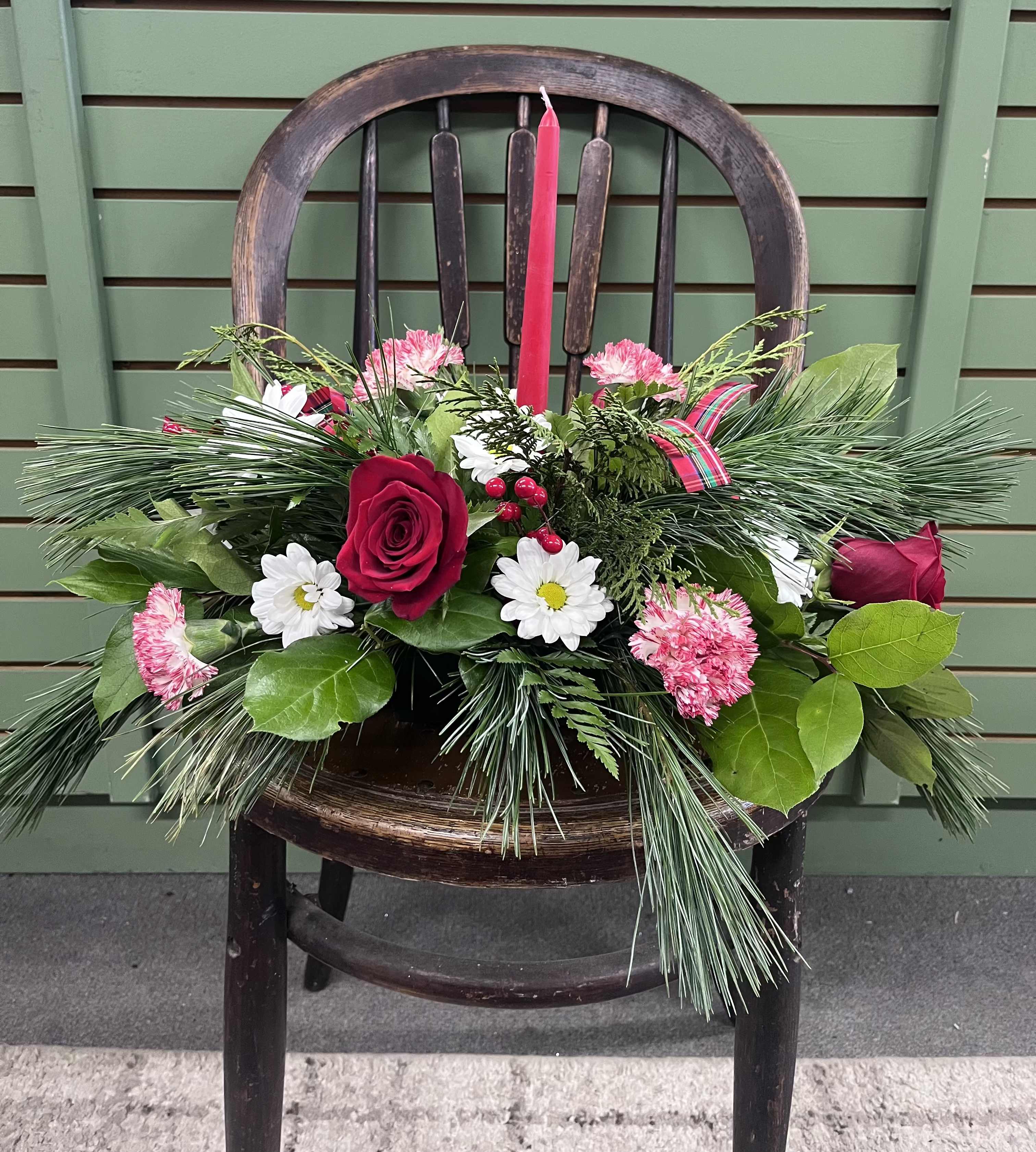 Glorious Gatherings - Impress your family members this holiday season with this glorious centerpiece! This beautiful centerpiece features a red candle, red roses, peppermint carnations, white daisies, berries, festive bows, and fragrant Christmas greens.  This centerpiece can also be created in other colors upon request. 