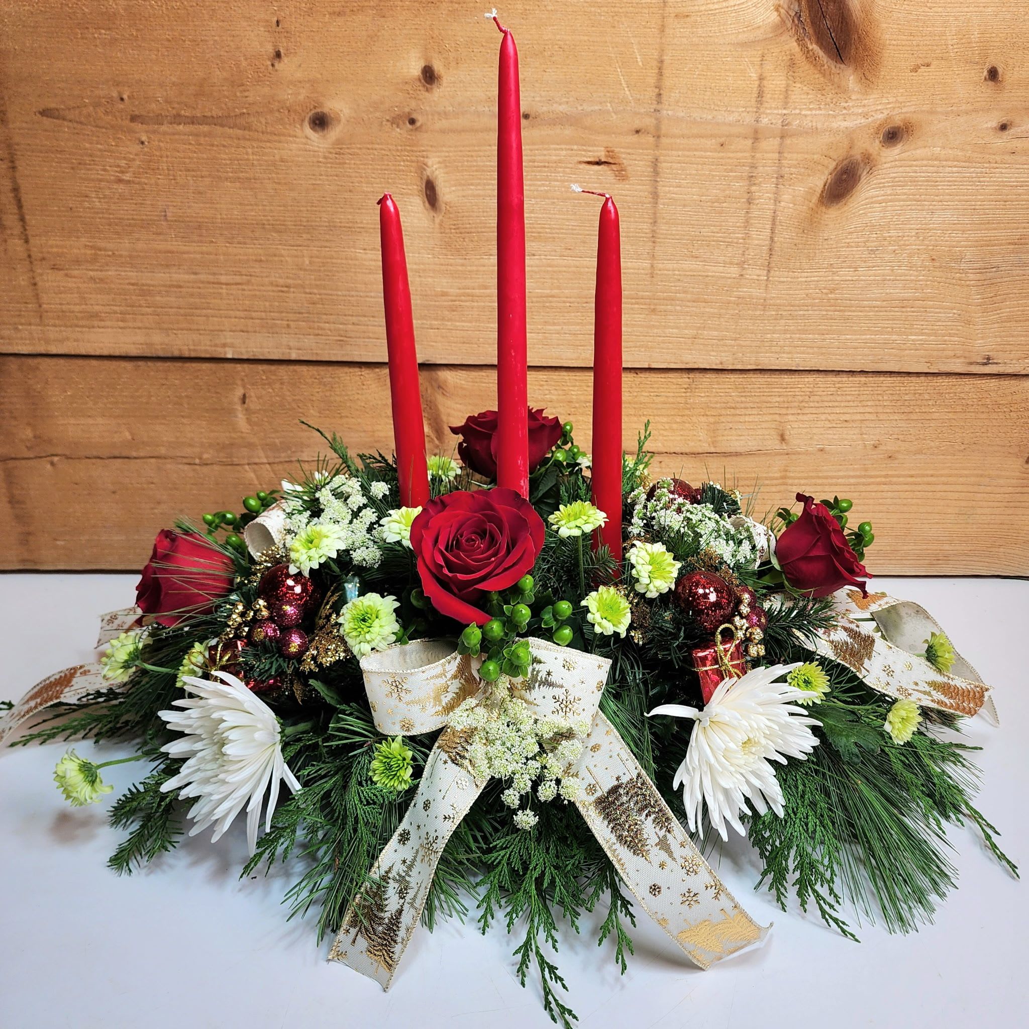 Lights of the Season Centerpiece - Our Lights of the Season Centerpiece is an absolute showstopper, designed to make your dinner table extra special this Christmas! With roses, mums, and queen anne's lace alongside decorative picks and bows, this design is also graced with three tapered candles to light up your holidays and make your memories bright this December! 