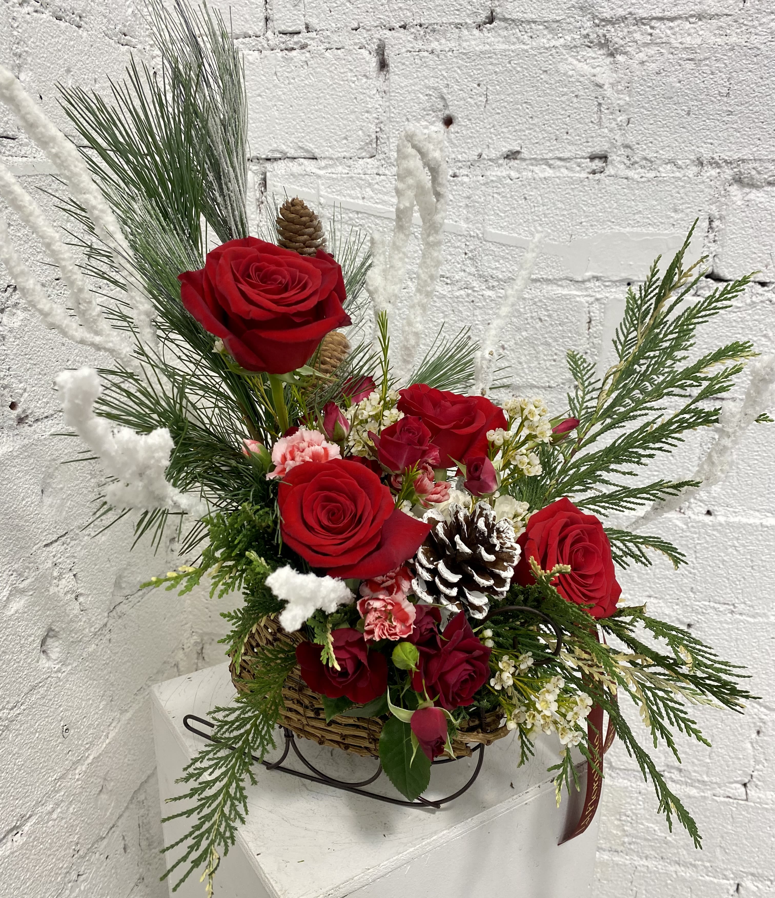 The Holly Sleigh - Beautiful Christmas Sleigh floral arrangement with snow brunches and pines.