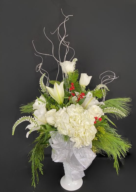 First Snowfall - Everyone could use a good snow day! Welcome in winter with this beautiful milk glass arrangement of hydrangeas, lilies, roses, veronicas and hypericum berries set against fresh cut pine.