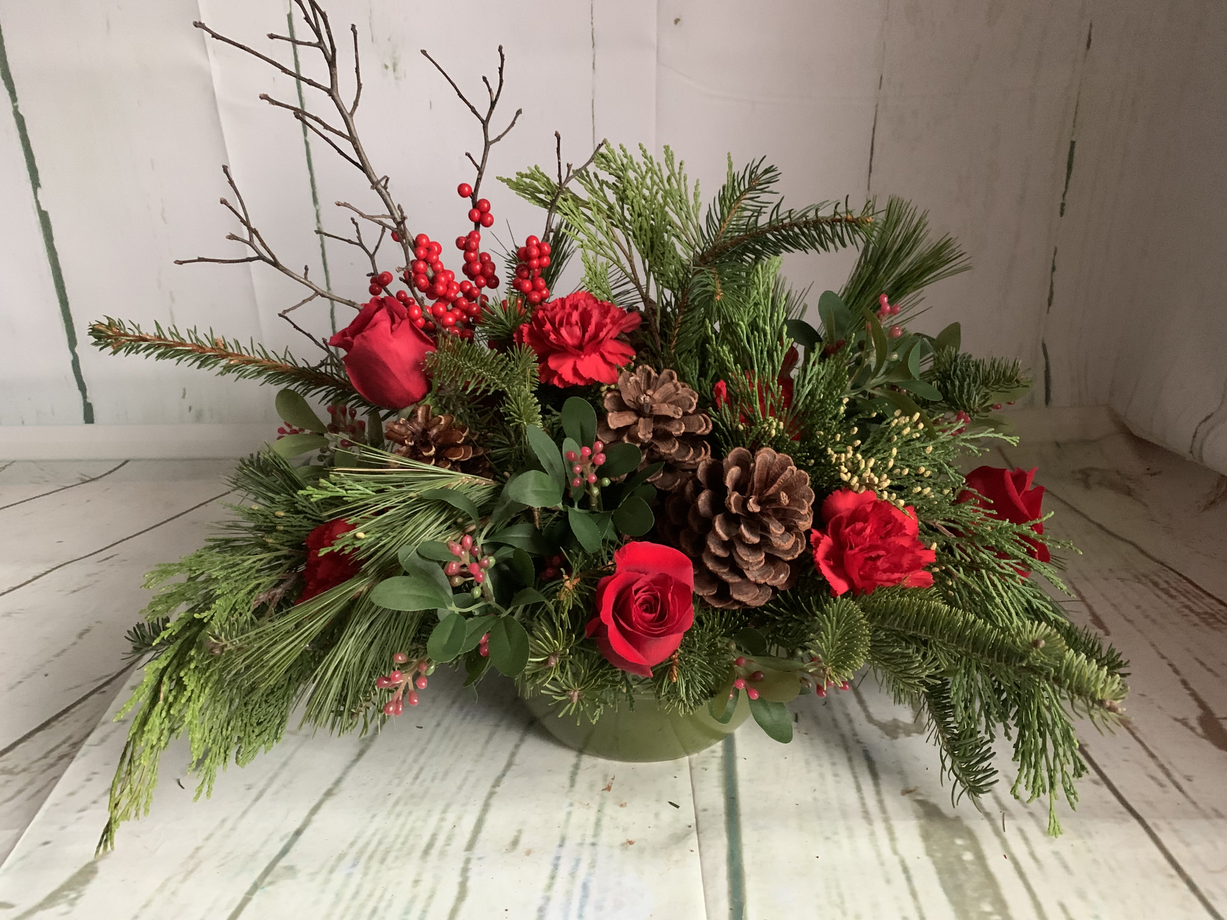 Enchanted Christmas - Celebrate the season with this charming centerpiece in a green ceramic pot, brimming with lush Christmas greens, pinecones, fresh flowers, and vibrant berries. Overflowing with festive elegance, it’s a perfect addition to your holiday table or a thoughtful gift to brighten any space.