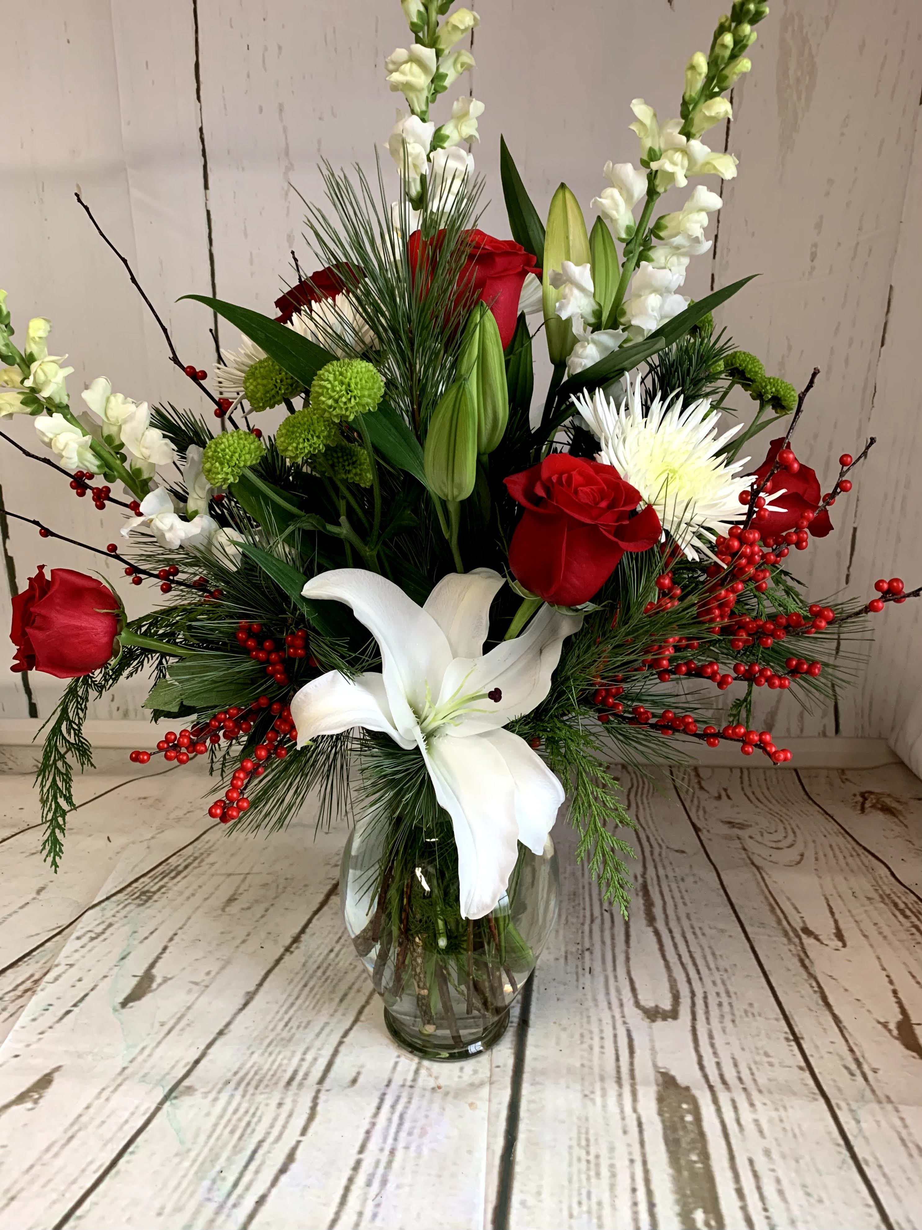 Merry &amp; Bright - Brighten your holidays with this fresh arrangement featuring elegant lilies, vibrant roses, and lush seasonal greens. Perfect as a festive centerpiece or a thoughtful gift, this design brings warmth and cheer to any space.