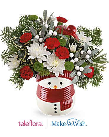 Teleflora's Frosty Wishes Bouquet - Whether it's filled with festive Christmas flowers or sweet treats, this cheerful frosty snowman treat jar vase brings whimsical winter cheer and joy to your loved one's face. The Frosty Wishes Bouquet includes miniature red carnations, green button spray chrysanthemums, and white cushion spray chrysanthemums, accented with variegated holly, white pine, and noble fir. It is beautifully presented in the Frosty Wishes Treat Jar, adding festive charm to any occasion. This charming Teleflora Exclusive snowman, with its great after-use as a wrapped candy jar, will be a hit for years to come.  