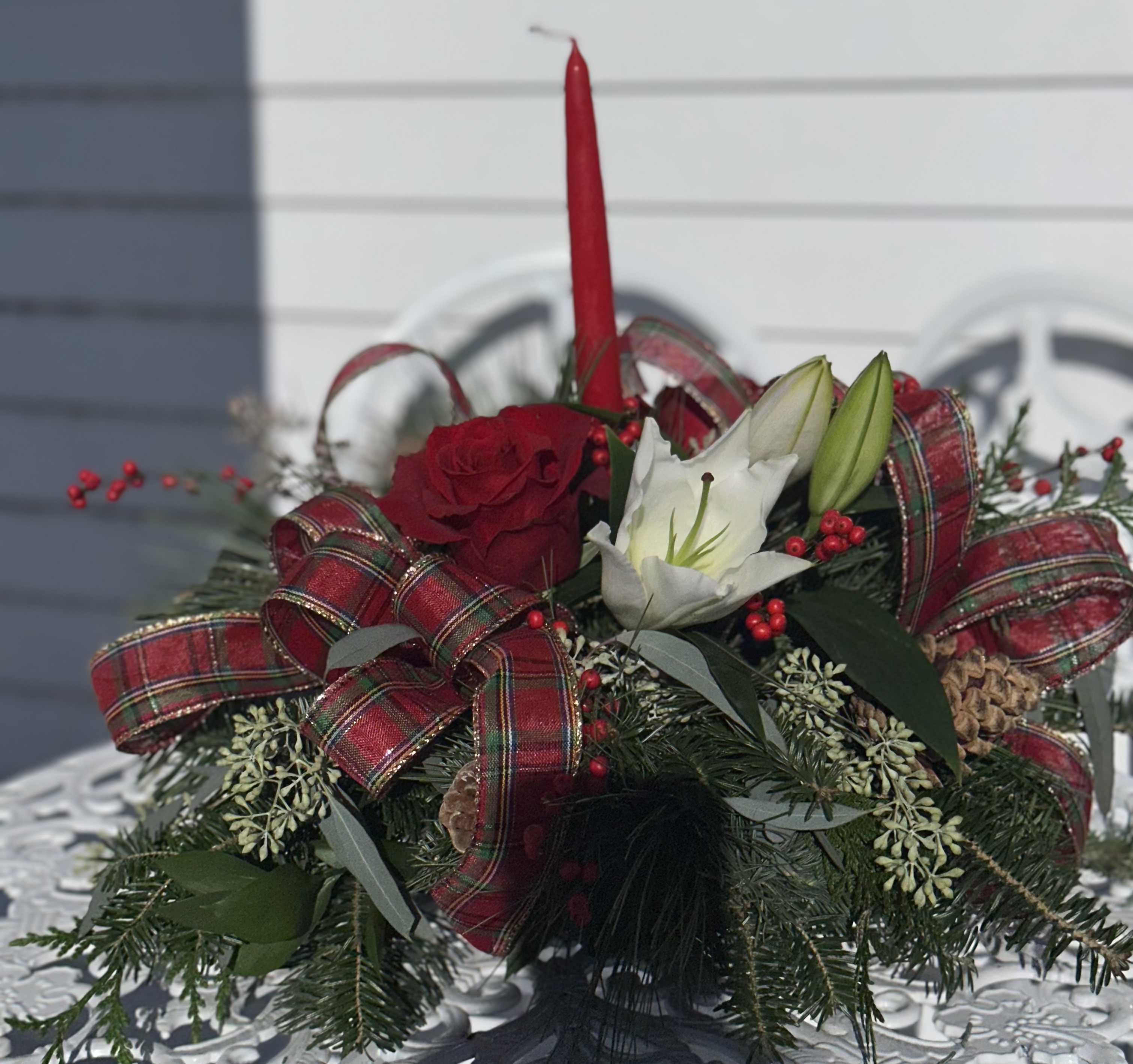 Yuletide Candle Centerpiece - Fresh Balsam, cedar, pine and seeded eucalyptus with red roses, white lilies, berries and Christmas plaid ribbon with a candle. Perfect for your Christmas gathering.