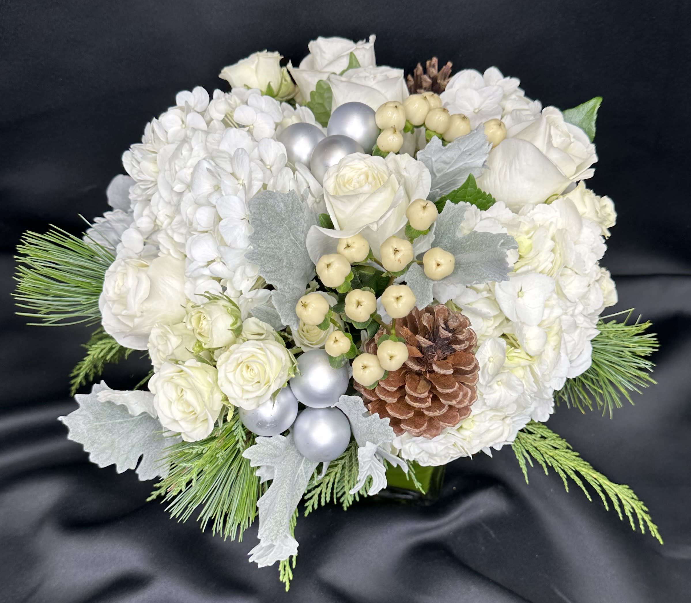 White Winter  - Snowy white florals of roses and hydrangea nestled in a bed of winter greens accented with holiday silver decor.
