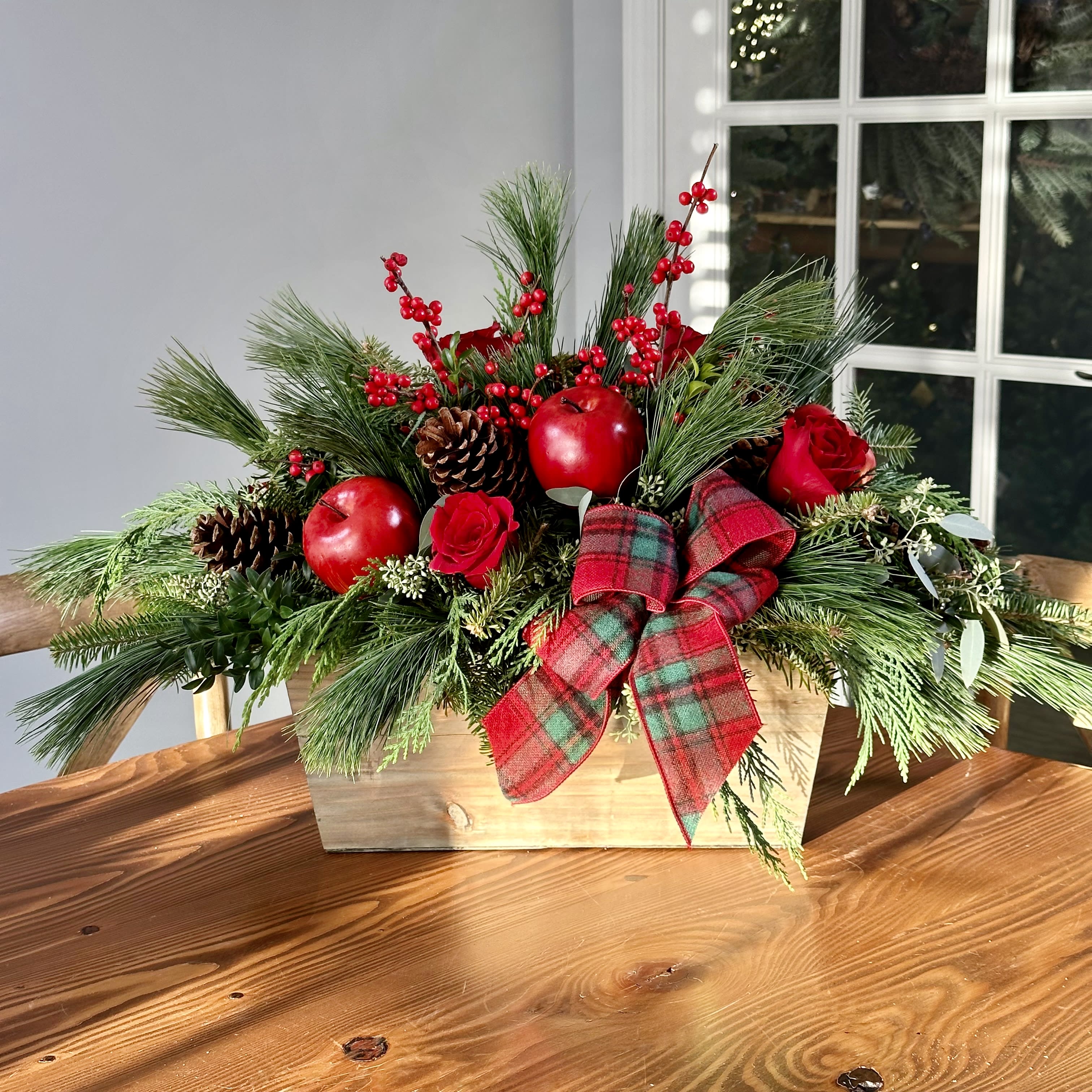 Country Christmas Charm Arrangement - Large wooden box overflowing with a beautiful mix of fresh winter greenery, berries, pine cones, faux apples, fresh roses and a ribbon accent. Flowers and Colors may vary. Available for LOCAL DELIVERY ONLY!!!