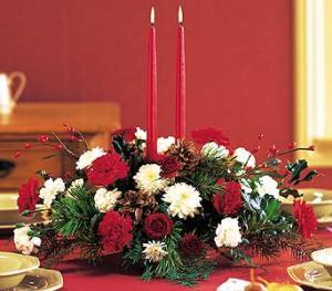 Winter Elegance Centerpiece - This is the perfect centerpiece for the season. Red carnations, red spray roses, white cushion poms accompany pine cones, berry accents, and 2 red candles. 