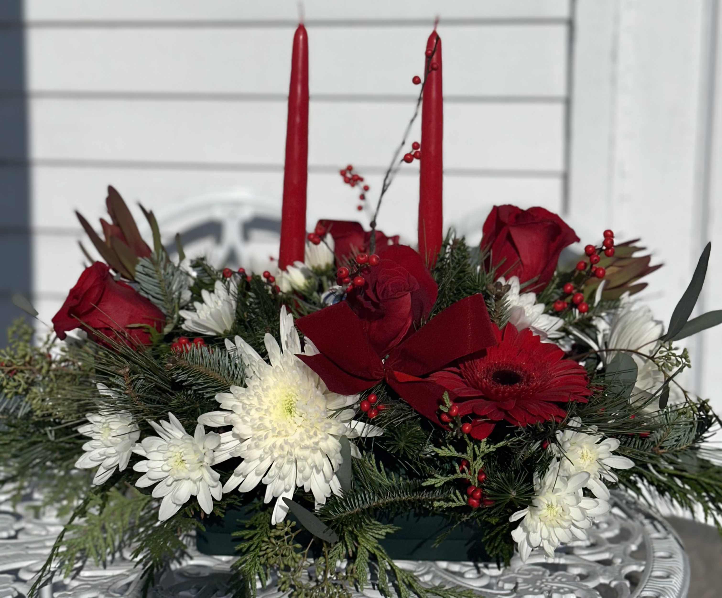Seasons of Love and Joy Centerpiece - 2 Candle centerpiece with red gerberas, red roses, white chrysanthemums, red berries, red velvet ribbon, filled with balsam, cedar and pine.