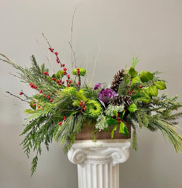 LAKESIDE HOLIDAY GREETINGS - This design brings the natural elements of the season indoors. Assorted winter greens such as white pine, juniper, holly, cedar, and balsam fill this natural wooden container accented with red berries and branches. 