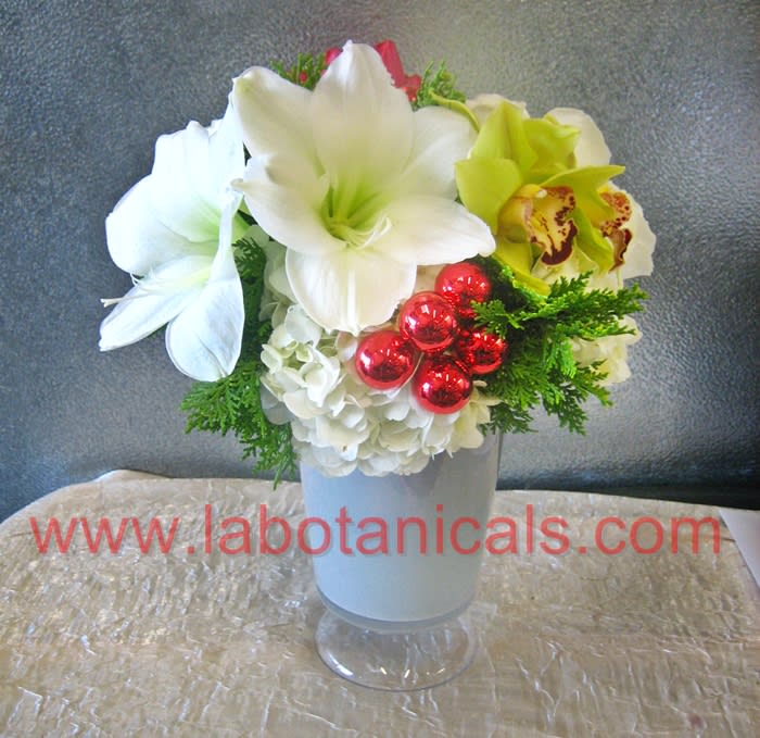 Amazing Amaryllis - The quintessential holiday flower, amaryllis have large, showy blooms which pair beautifully with orchids and hydrangeas, as shown. Accented with roses and ornaments, this is a wonderful holiday gift. Approx. 18&quot; tall x 10&quot; wide.