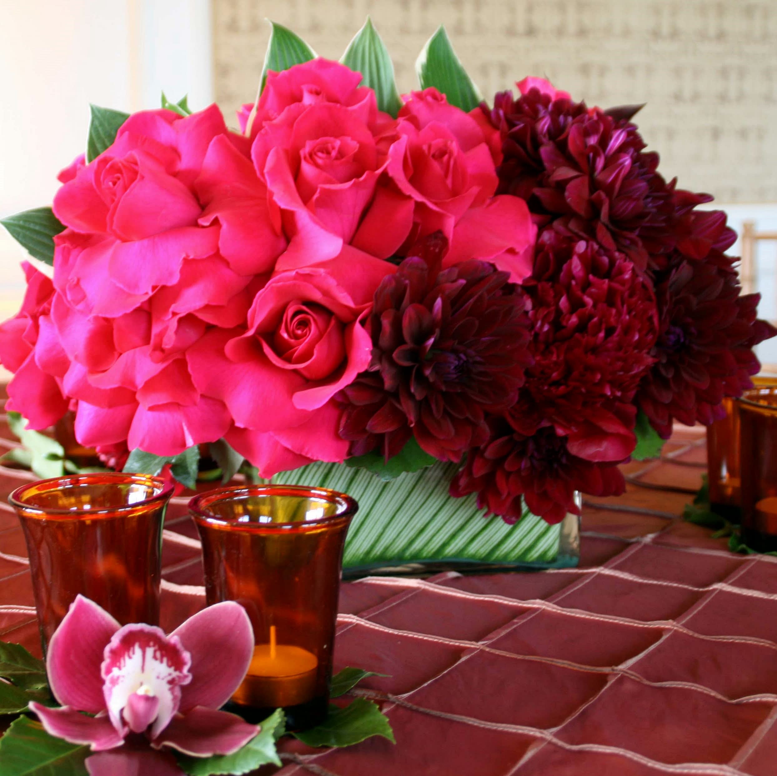 Bejeweled Delight - This spectacular design can be used equally well as a dining table centerpiece or a gift for a loved one. Drenched in dazzling shades of fuschia, berry, plum and burgundy, this bouquet features velvety roses and peonies, along with exotic leaves for a tasteful accent. Approx. 13-14&quot; square.