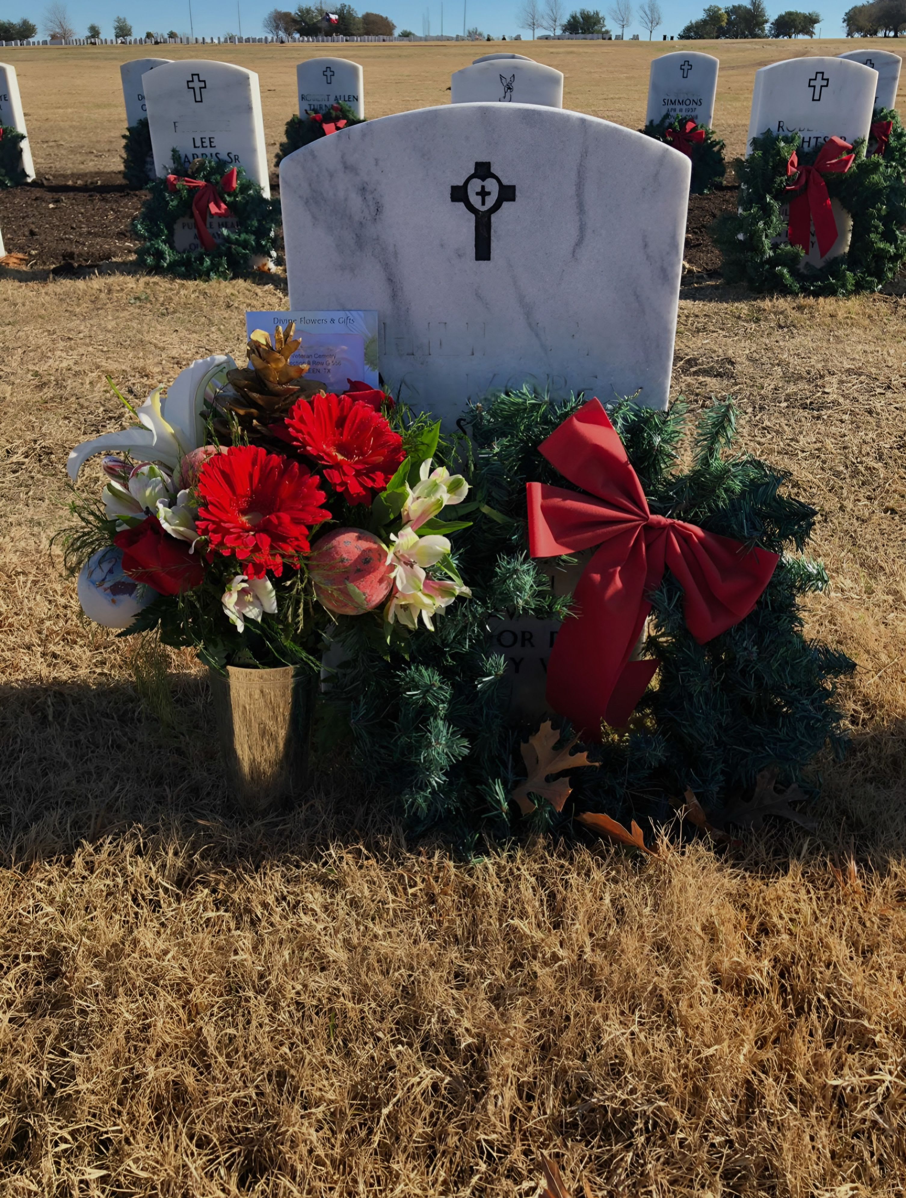 Holiday Wreath  - Honor the memory of a loved one with this beautiful Holiday Cemetery Wreath, thoughtfully crafted to bring warmth and remembrance during the Christmas season. Lush evergreen branches form a classic circular wreath, symbolizing eternal love, and are accented with rich red berries, pinecones, and festive holiday ribbon. The design is both elegant and durable, made to withstand winter weather while offering a peaceful, timeless tribute. Perfect for placing at a gravesite, it serves as a gentle reminder that those we love are always in our hearts during the holidays.