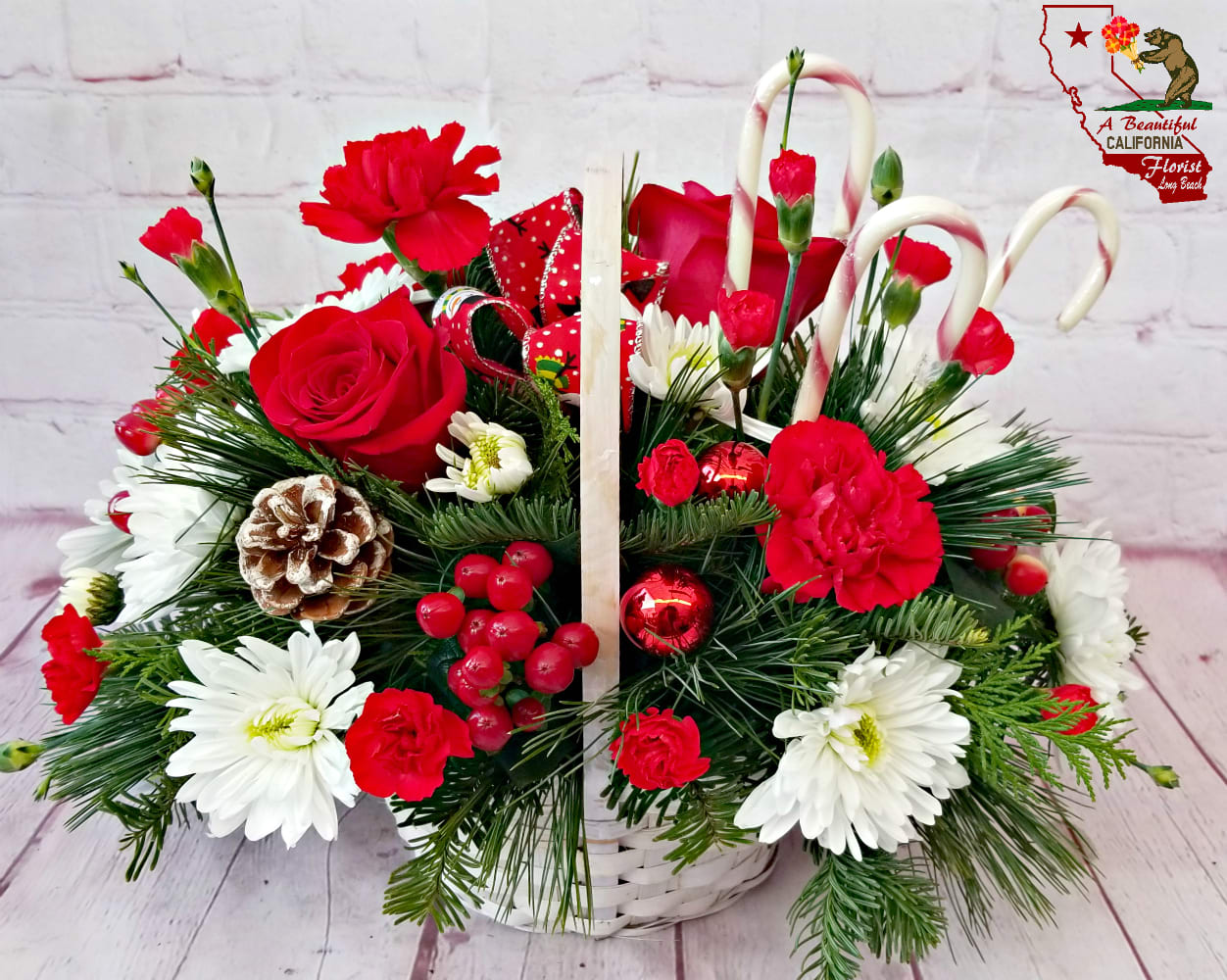 Candy Cane Basket - Delight someone with this wicker basket filled with holiday evergreens, long lasting red &amp; white flowers and real candy canes!