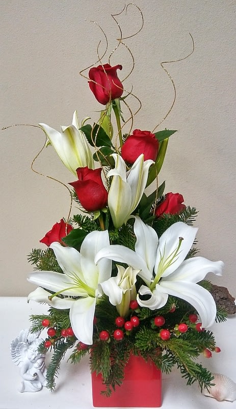 Merry Christmas to You - This arrangement of holiday cheer with red roses and white lilies with hypericum berries in a red vase is the perfect christmas gift to send to a friend or loved one.The vase may vary depending on availability.