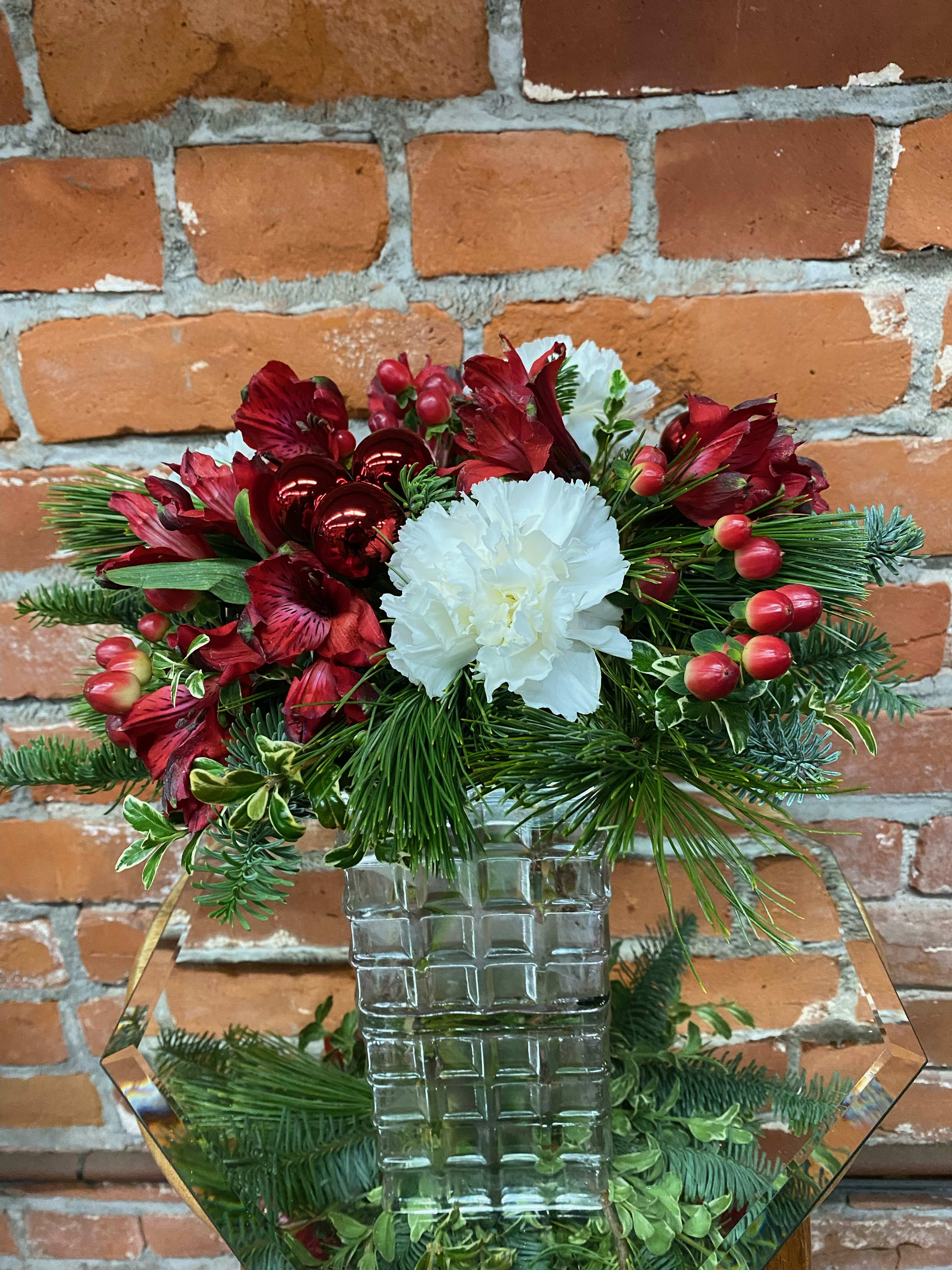 Holly Jolly - Gift someone a holly jolly holiday with this adorable, compact arrangement. This sweet arrangement is filled with some really long lasting goodies; including carnations, alstromeria, and hypericum berries! Completed with red ornaments and fresh Christmas greens. 