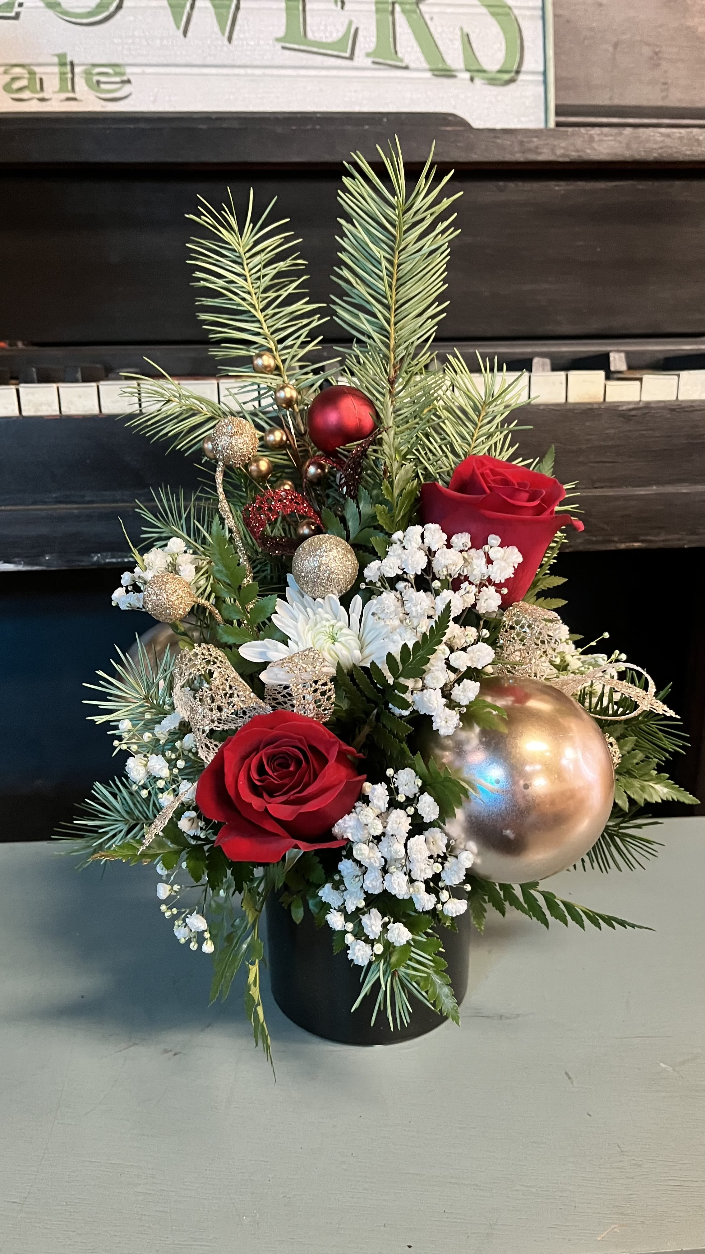 Christmas Tree  - Send out this lovely Christmas tree arrangement. This designers choice Christmas themed arrangement is ideal for the season , especially as a centerpiece for everyone to enjoy. our designer will pick out a fresh selection of florals ideal for Christmas and placed in a nice bottom piece. It is approximately 14” tall and 8 inches wide. Pictures shown represent an overall idea , not an exact replica of the possible outcome. 