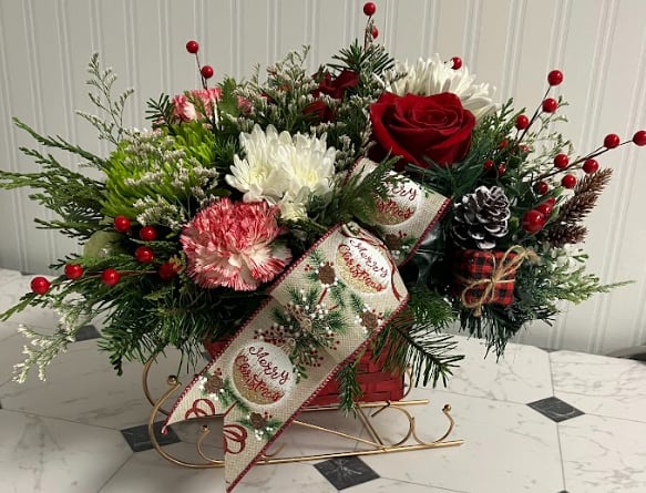 Santa's Magic Sleigh - Deliver holiday joy with Santa’s Magic Sleigh, a whimsical arrangement bursting with red, white, and green blooms. Designed in a charming sleigh container and finished with a “Merry Christmas” ribbon, this festive favorite makes the perfect décor piece or cheerful holiday gift.