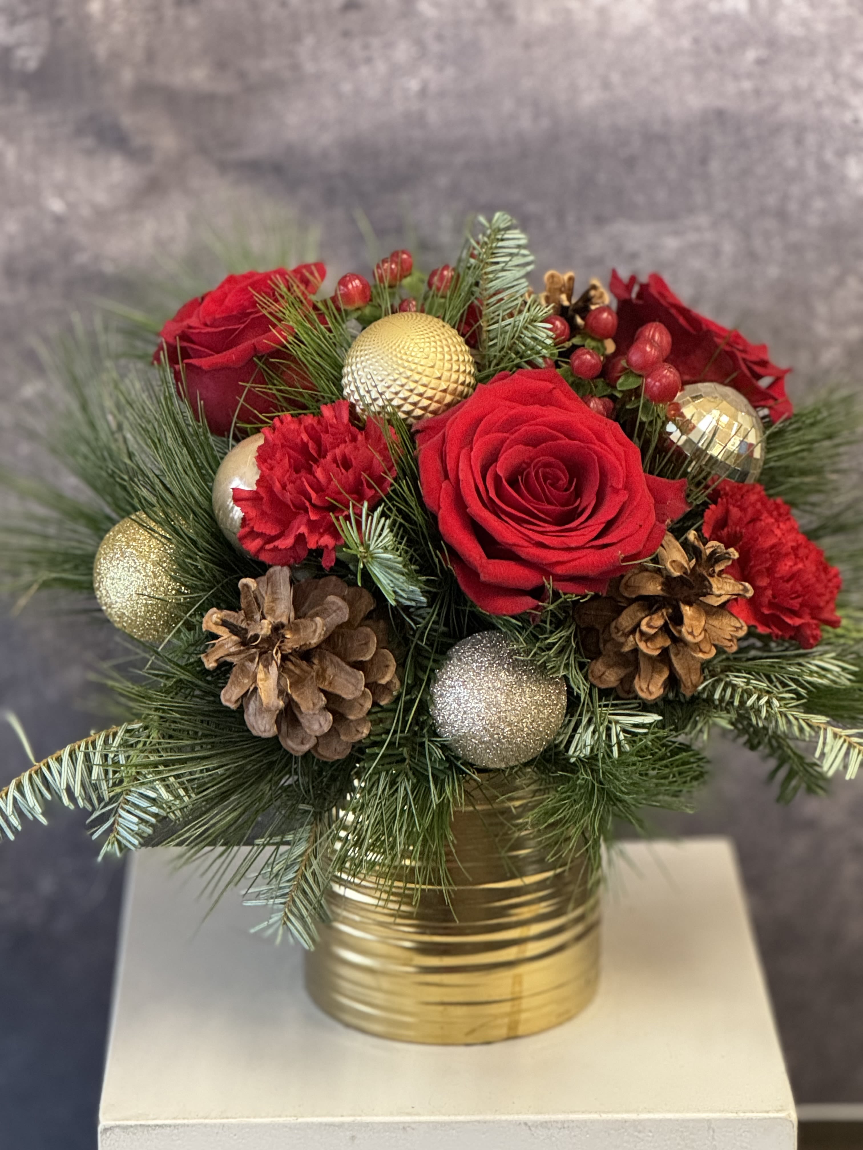 Festive Gold - This gorgeous centerpiece is arranged in a ceramic gold vessel and features red roses, red carnations and holiday ornaments.  It is approximately 10 x 10. We select the freshest blooms of the season and flowers may vary.