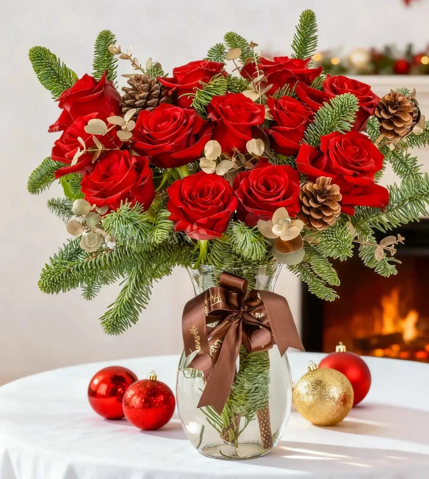 Lush Red roses Christmas Arrangement  - A timeless expression of festive beauty, the Holiday Scarlet Elegance Vase brings together lush red roses, fragrant Christmas greens, and warm seasonal accents for a rich, luxurious holiday display. The vibrant blooms paired with fresh spruce, golden eucalyptus, and pinecones create a cosy, sophisticated look that instantly elevates any space. Set in a clear glass vase and finished with a premium ribbon, this arrangement feels warm, classic, and perfectly festive — ideal for gifting or creating a striking seasonal centrepiece at home.