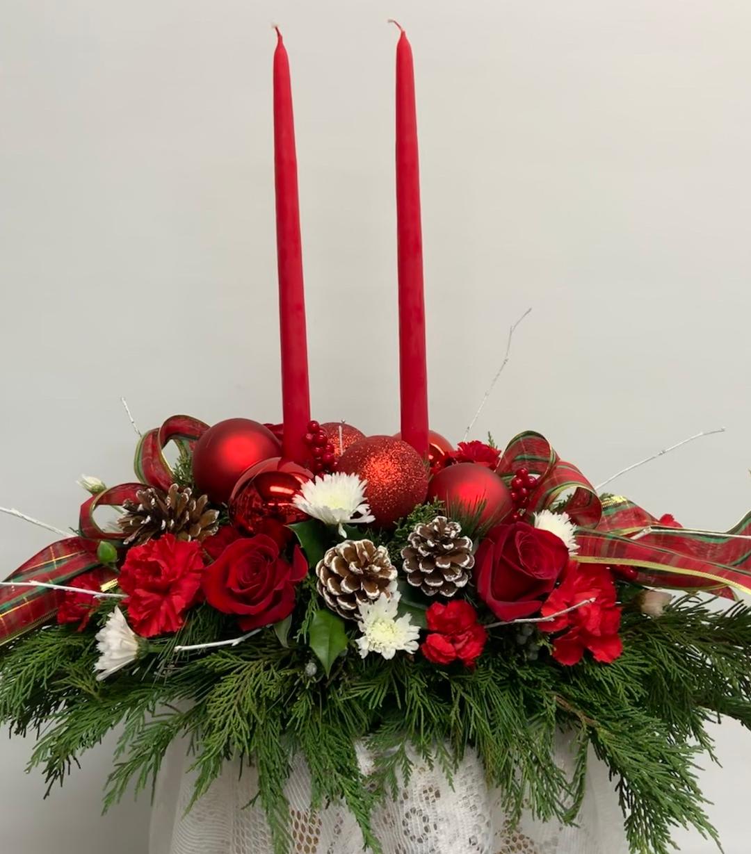 Christmas on the South Shore - Send Holiday cheer with this Centerpiece of Joy.  The calorie free option for the dinner table! Arranged with winter greenery and an assortment of flowers including roses, carnations, mums, with pinecones, large Christmas balls and ribbon all adorned with taper candles.