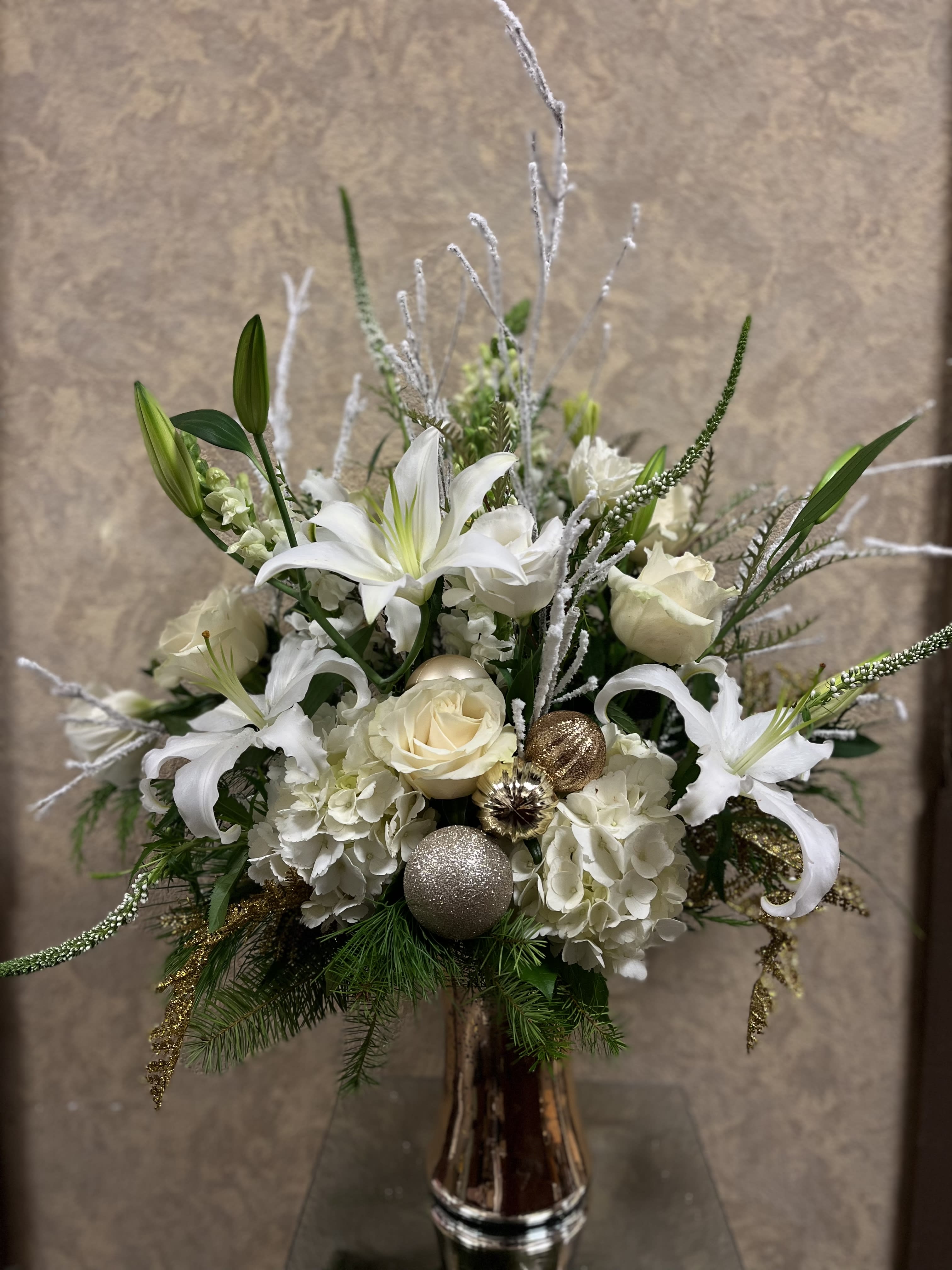 A Golden Christmas - Happy Golden Days! Wish someone a happy new year with this elegant design. This arrangement includes white lilies, snapdragons, roses, lisianthus, hydrangeas, veronicas, and holiday fillers in a beautiful gold vase. Seasonal: Holiday Design View: Symmetric Front Facing View Photo shown: Standard 