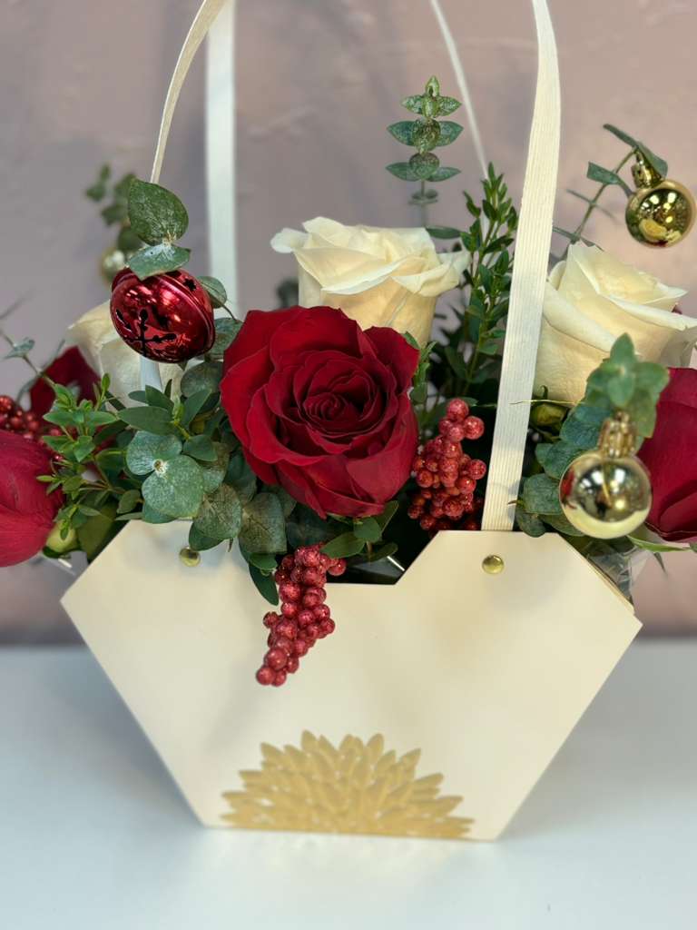 Winter Luxury Holiday Purse Arrangement - Celebrate the beauty of the season with our Winter Luxury Holiday Purse Arrangement, a chic and festive design crafted in a white purse-style box with gold detailing. This arrangement features premium red roses, white roses, fresh eucalyptus, and elegant holiday accents in gold and red for a sparkling, sophisticated look. Perfect for Christmas gifting, home décor, or surprising someone special with a unique and stylish holiday piece. Each arrangement is handcrafted in our Yorba Linda floral studio, ensuring freshness, quality, and exclusive design.  Ideal for dining tables, desks, reception areas, and seasonal gifting.  Fresh flowers, modern design, and a luxurious finish.  Same-day local delivery available.