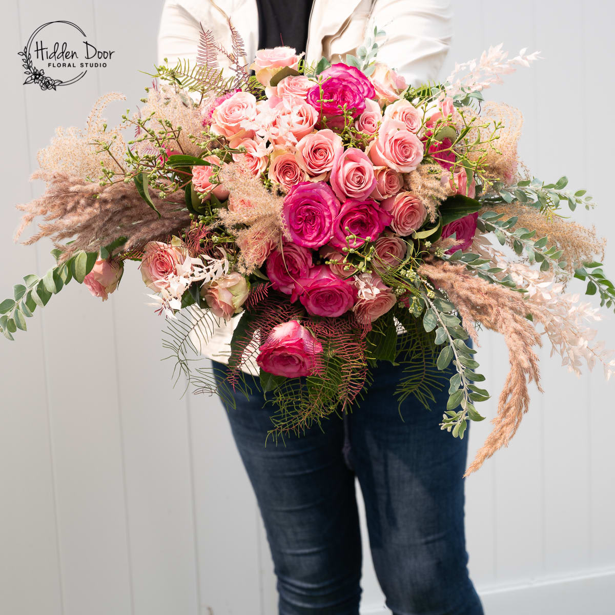 Cinderella - Cinderella is a soft, romantic arrangement built around rich pink roses, airy pampas, and delicate seasonal textures. The silhouette is sweeping and feminine, with gentle movement and layered greenery that create an elegant, storybook feel. A luxurious, modern take on classic romance. Please Note: Our arrangements are handcrafted, and no two pieces are ever identical. Variations in flower types, color tones, and exact placement will occur based on daily availability. We do not create factory-duplicate designs — instead, we recreate the style, palette, and overall feel of the arrangement while ensuring every piece is fresh, beautiful, and premium.