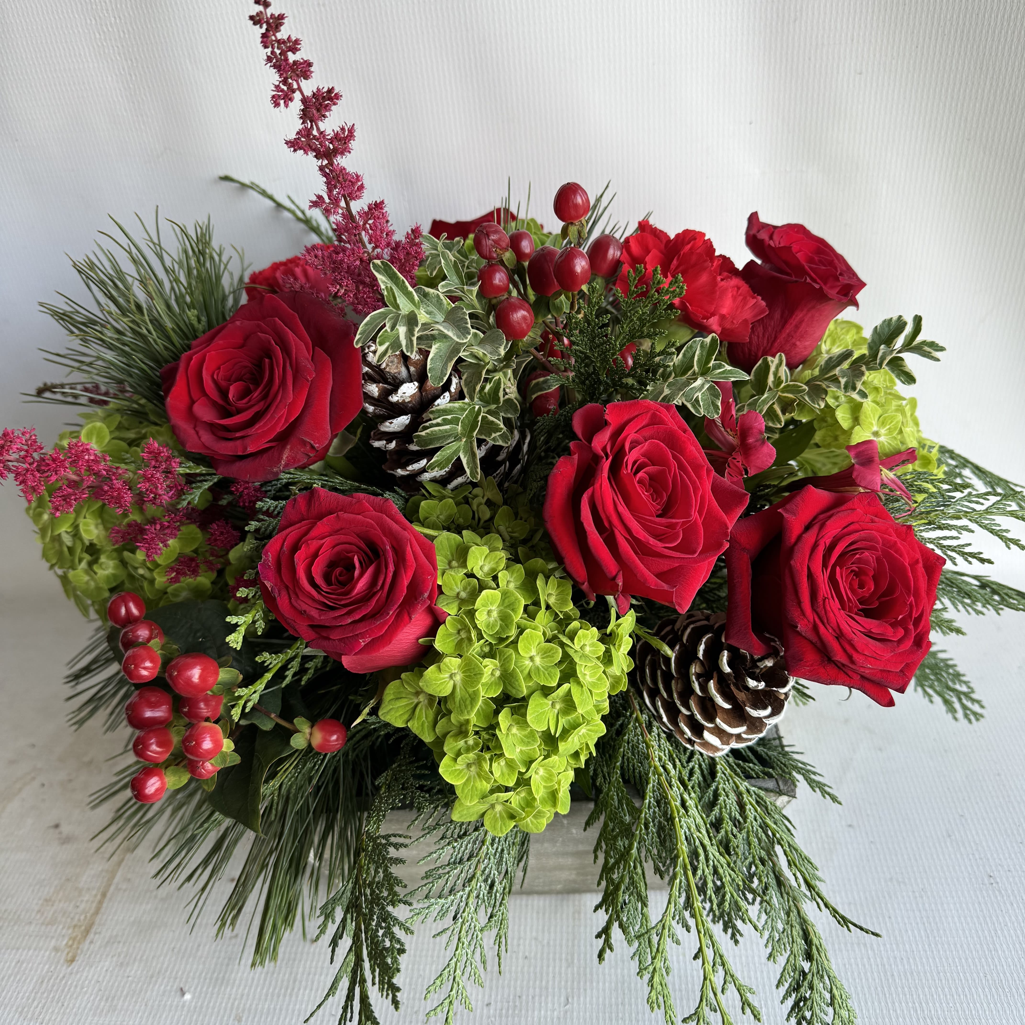 Winter Delight - Red roses, green hydrangeas, blue thistle, seeded eucalyptus and hanging amaranths fill this silver cub container.