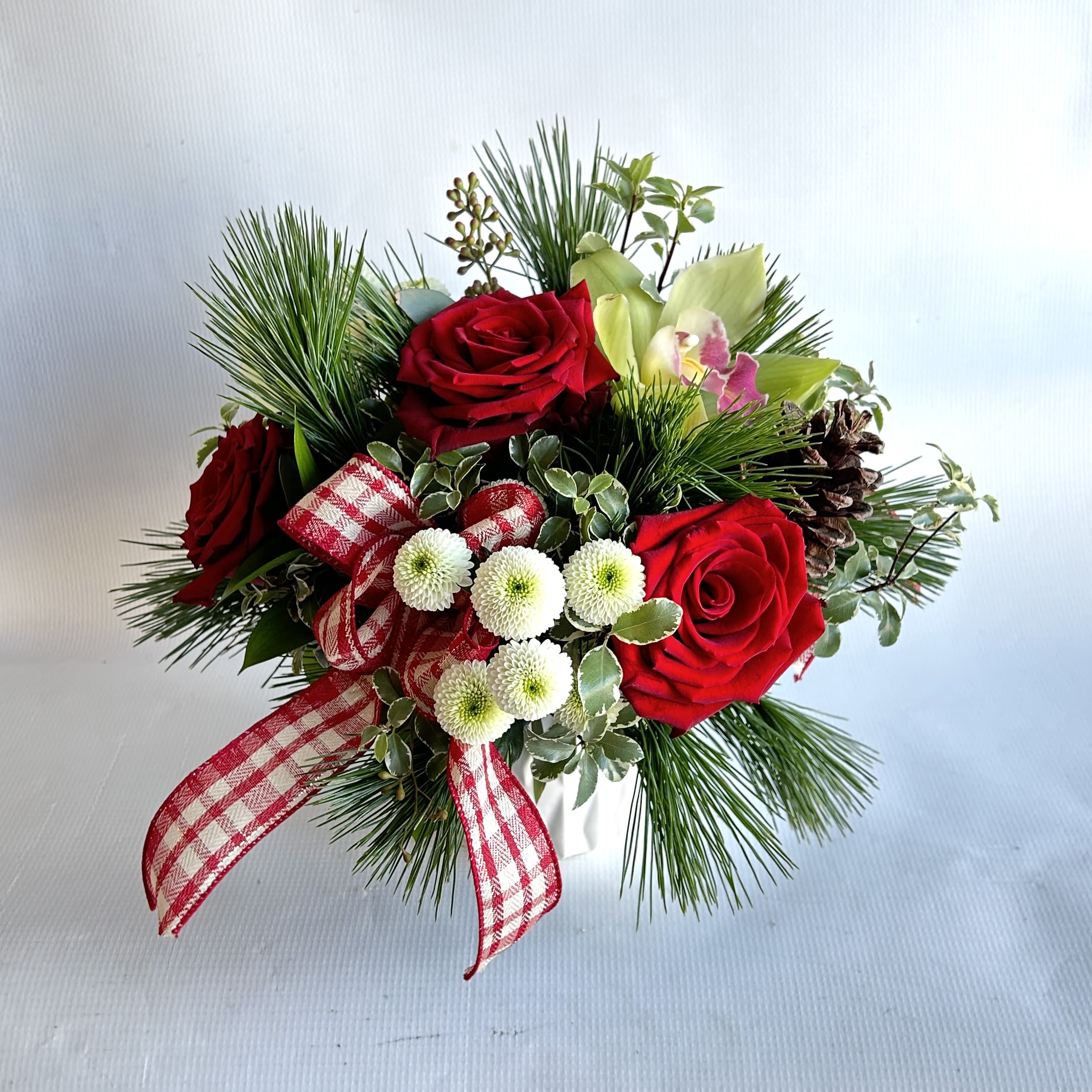 Happy Holidays - A statement piece with holiday greenery, red roses and orchids including a Voluspa holiday candle.