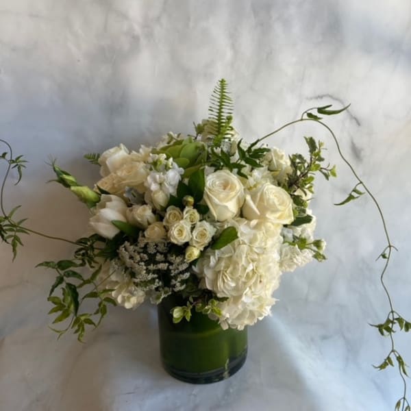 The Celtic - Elegance and simplicity come together in this stunning clear cylinder vase arrangement. White blooms accented with a delicate green ribbon create a timeless and versatile gift that is perfect for any occasion. Measuring approximately 12 inches tall by 8 inches wide, this arrangement is sure to make a statement.