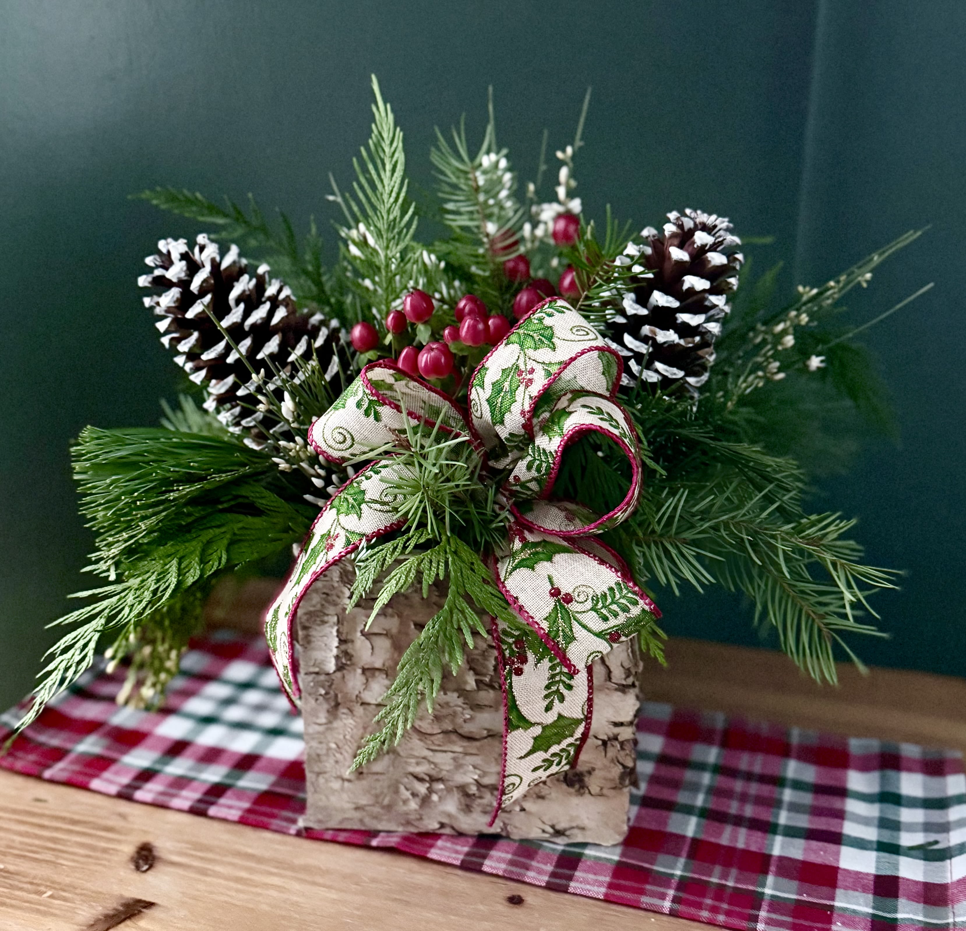 Rustic Birch Centerpiece  - A birch cube container, filled with a mix of winter greens, berries, pine cones and a rustic bow. 