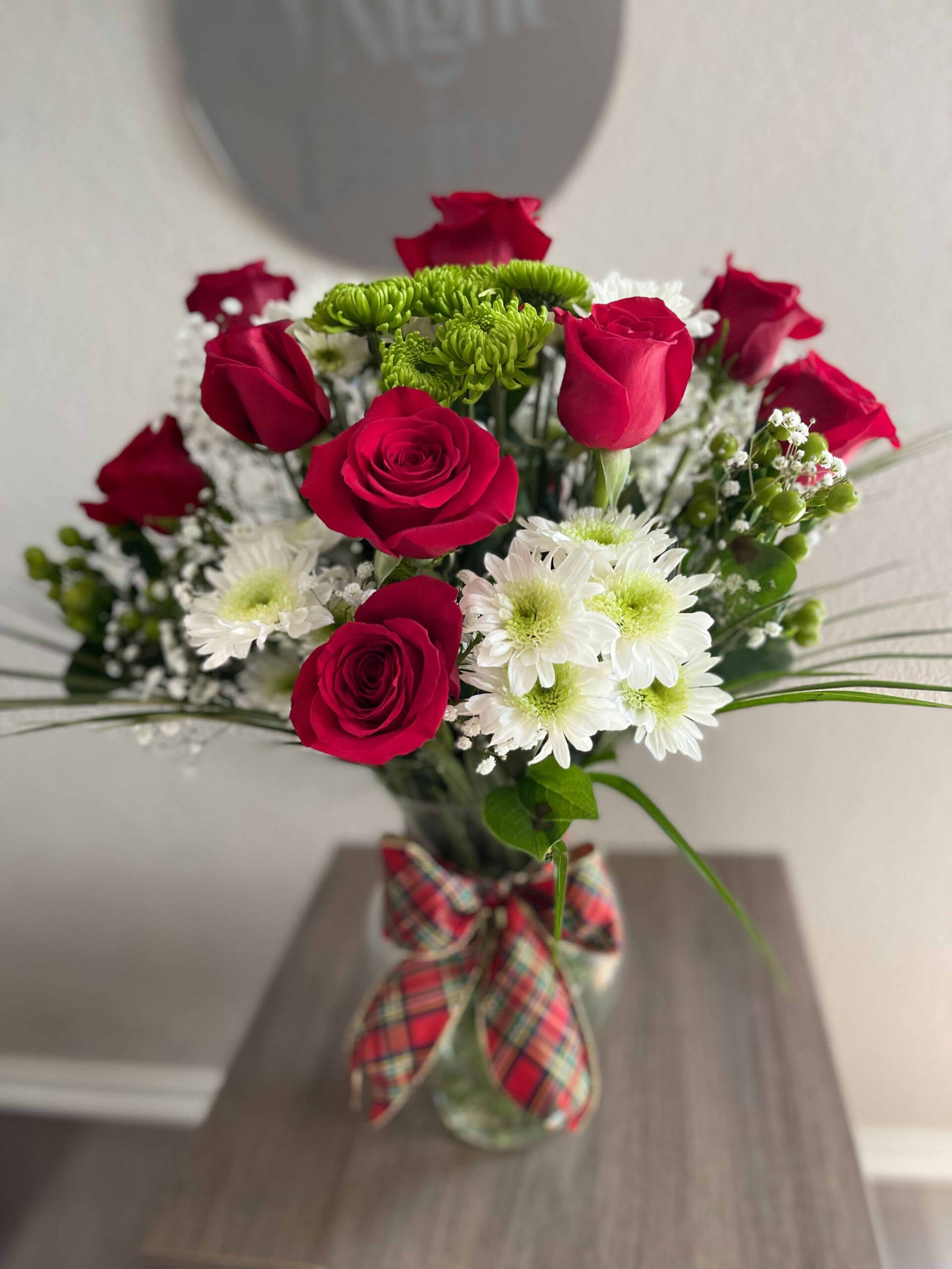 Joy Ride - Share this joyous and seasonal arrangement with a loved one. Displayed are elegant classic red roses. White and green chrysanthemums add contrast and texture, while Baby’s Breath adds a certain delicacy. With a touch of assorted greens, this arrangement is fixed in a clear vase with a delicate bow.