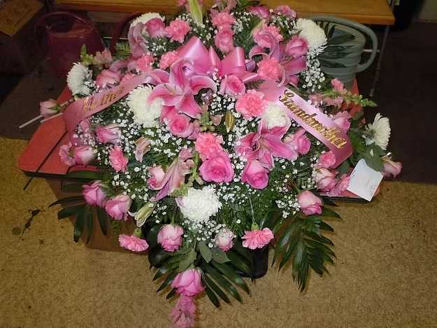 C12 Casket Spray - A mixture of white fuji mums, sweet unique roses, pink carnations, pink lilies,  greens, and baby's breath.    Banner - $15.00 + extra  Substitutions may apply, pending flower availability.
