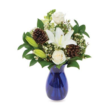 Season Of Giving Bouquet - The essence of elegance, this alluring floral creation is certain to be admired and cherished by anyone who receives it! Asiatic lily, roses, snapdragons, waxflower and pine cones are arranged beautifully in a cobalt blue jordan vase.