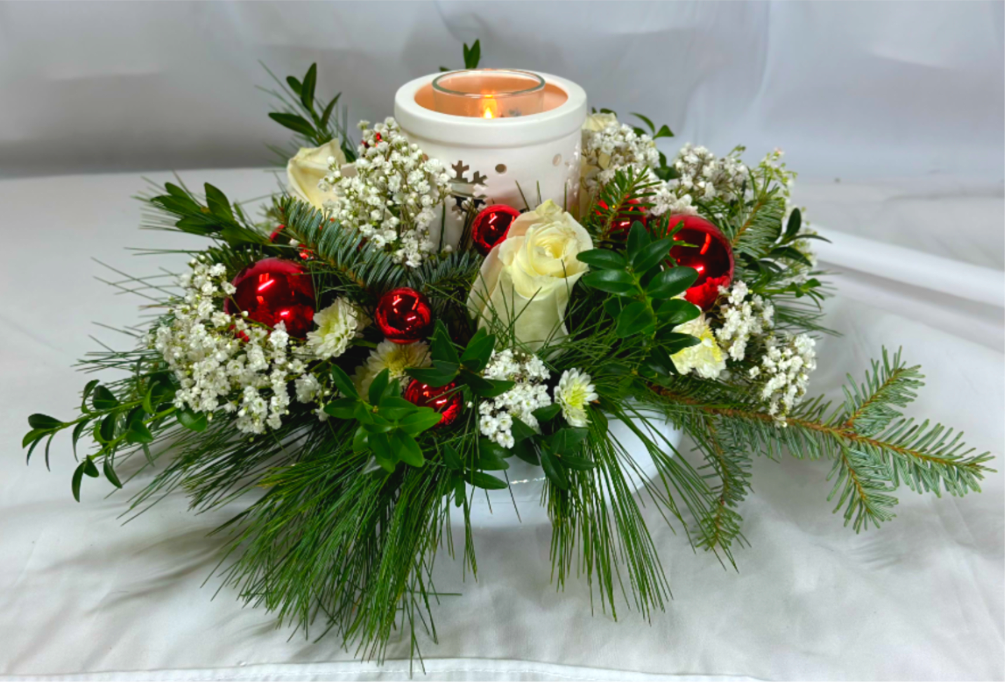 Circle of Light - This Christmas flower arrangement is so versatile and pretty. It's a Leary's Flowers exclusive design that features a center candle sconce and container a tealight for a warm holiday glow in the center of beautiful winter flowers. The Tealight holder, vase, and sconce can be reused year after year, and would be  lovely as a centerpiece, or on any table in your home. If the featured flowers are not available we will design your arrangement with the freshest flowers of equal or greater value.