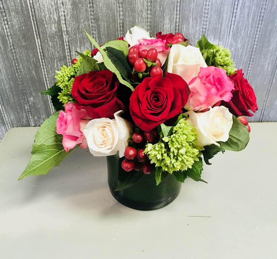 Winter Roses - Roses in pink, red and white with red hypericum berries and hydrangeas in a simple cylinder vase with a leaf lining the inside.