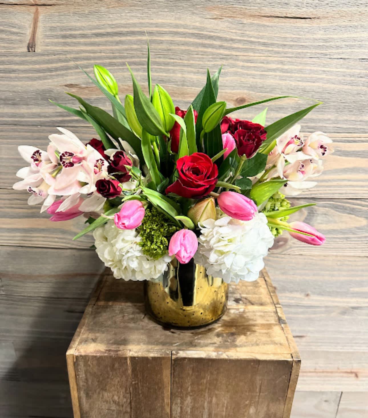 Love Birds - This stunning piece is the contemporary floral lover's dream.  Featuring roses, spray roses, hydrangeas, cymbidiums, tulips and berries in a beautiful gold mercury glass container.