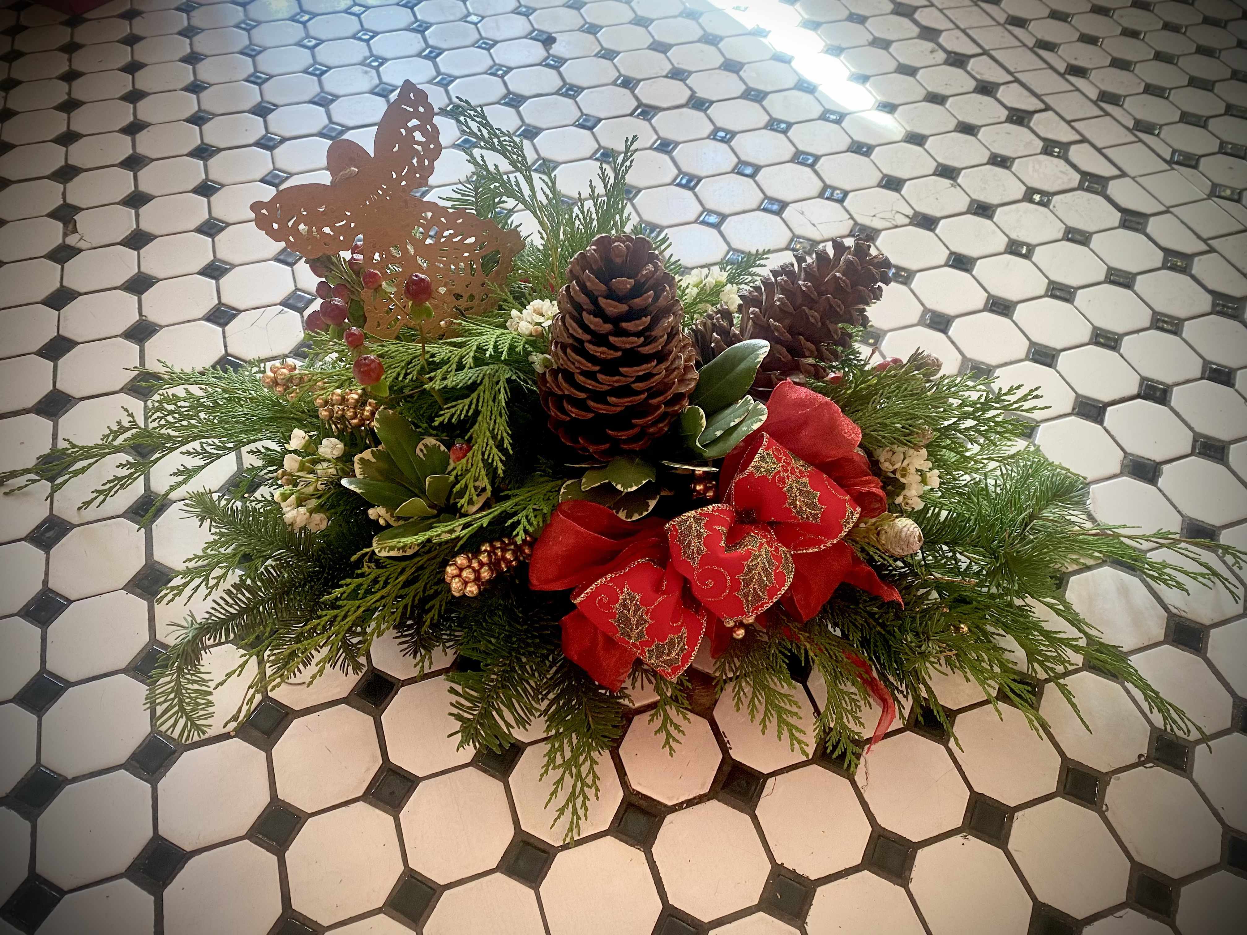 Christmas Antiquity - Christmas Antiquity brings together the nostalgic, traditional colors and scents of Christmas into a long and low centerpiece perfect for your holiday table. This arrangement features an assortment of Nobel Fir and Port Orford Cedar along with berries, pinecones, a keepsake ornament and bow.   