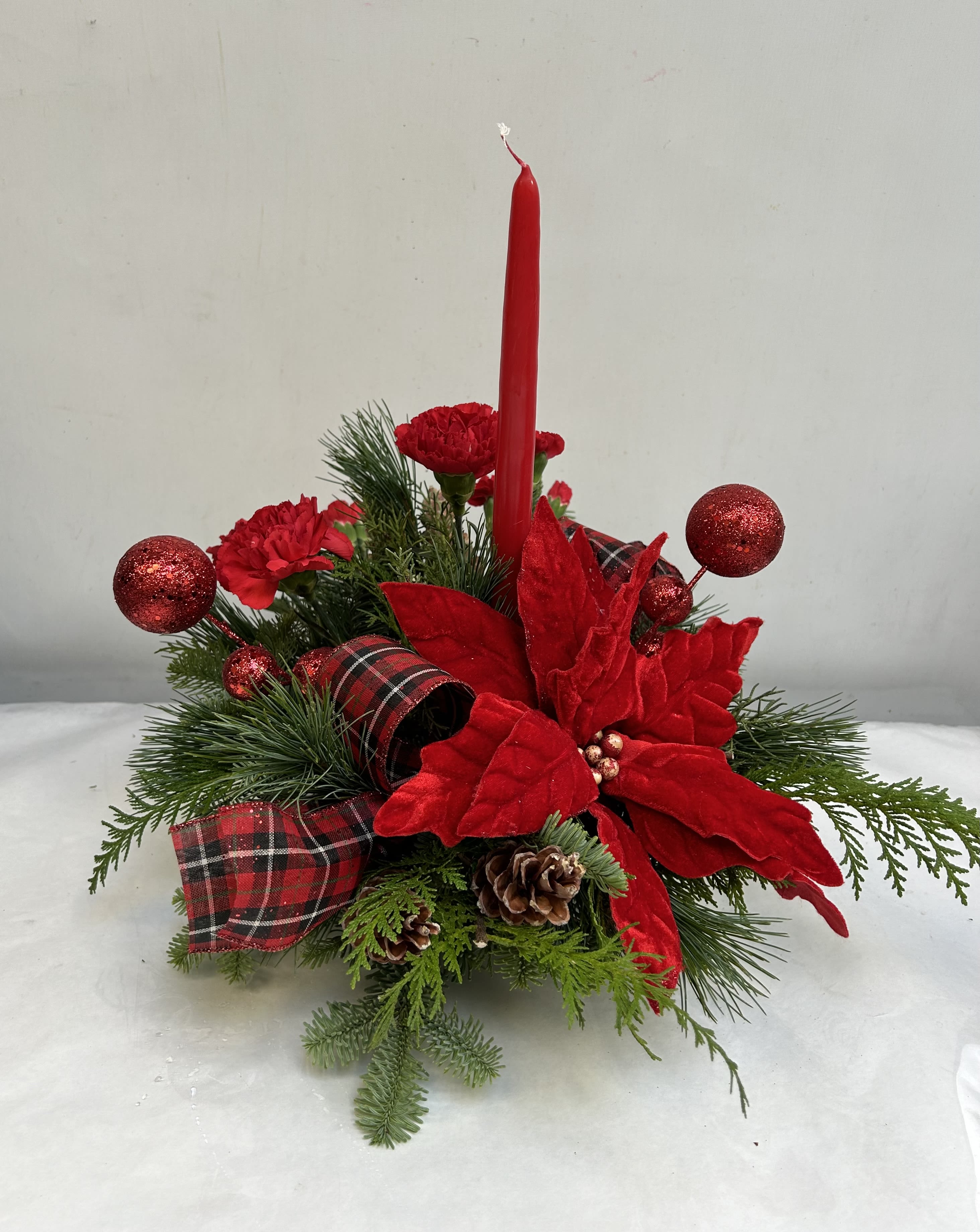 Light My Christmas - This basic single candle centerpiece is anything but basic. Want a different color? Let us know in the special instructions and we will do our best to make it happen! Lush mixed pine, red winterberries, roses carnations and festive MM balls.  HFS 1201-2 