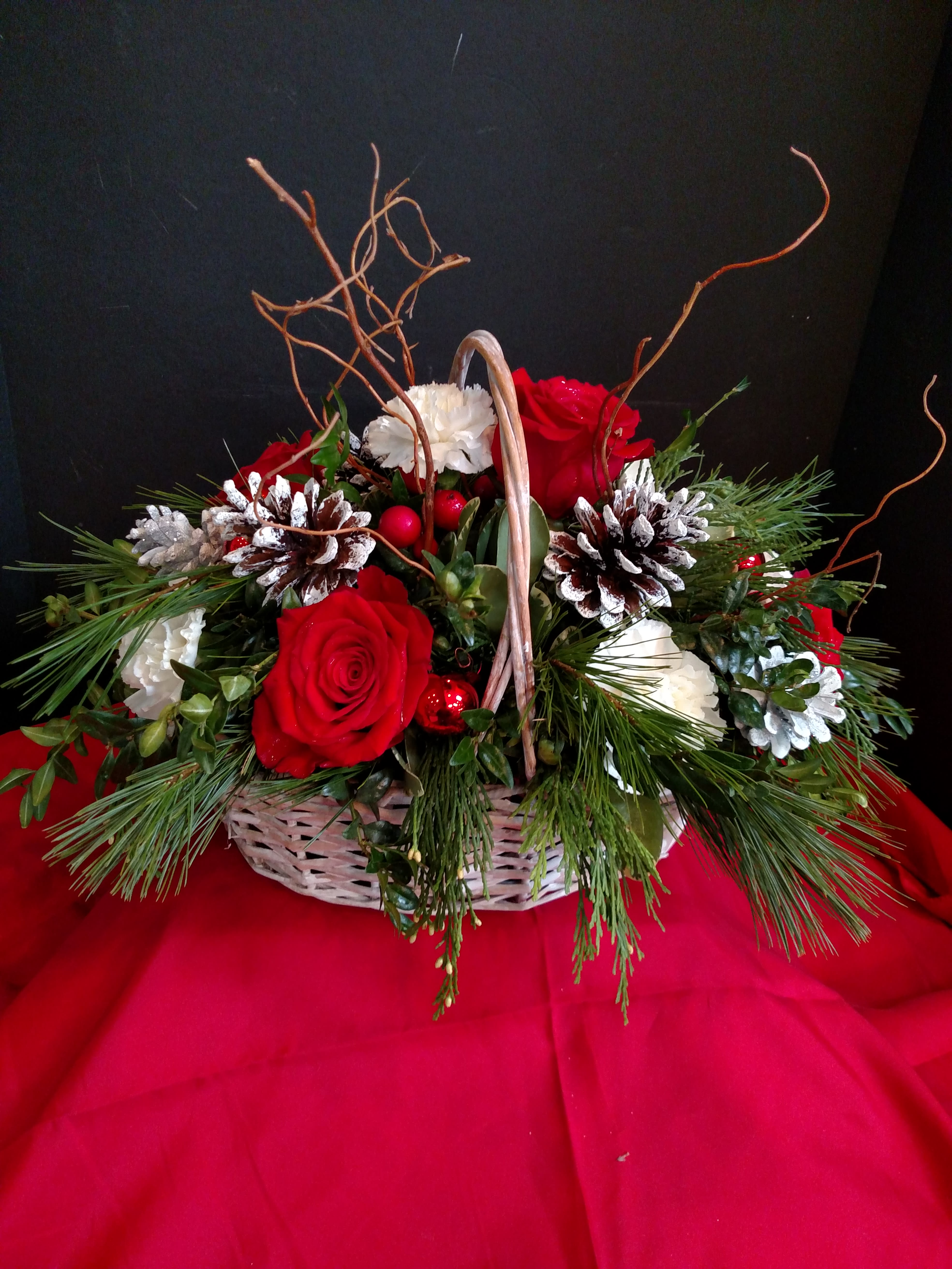 Christmas Centerpiece - Classic Christmas basket with holiday greens, pine cones and red and white flowers.
