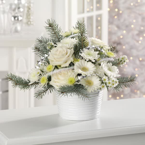 White Christmas Tin - Snowy white roses, gerber daisies, glittery garland and pine boughs, container may vary with avaliability.