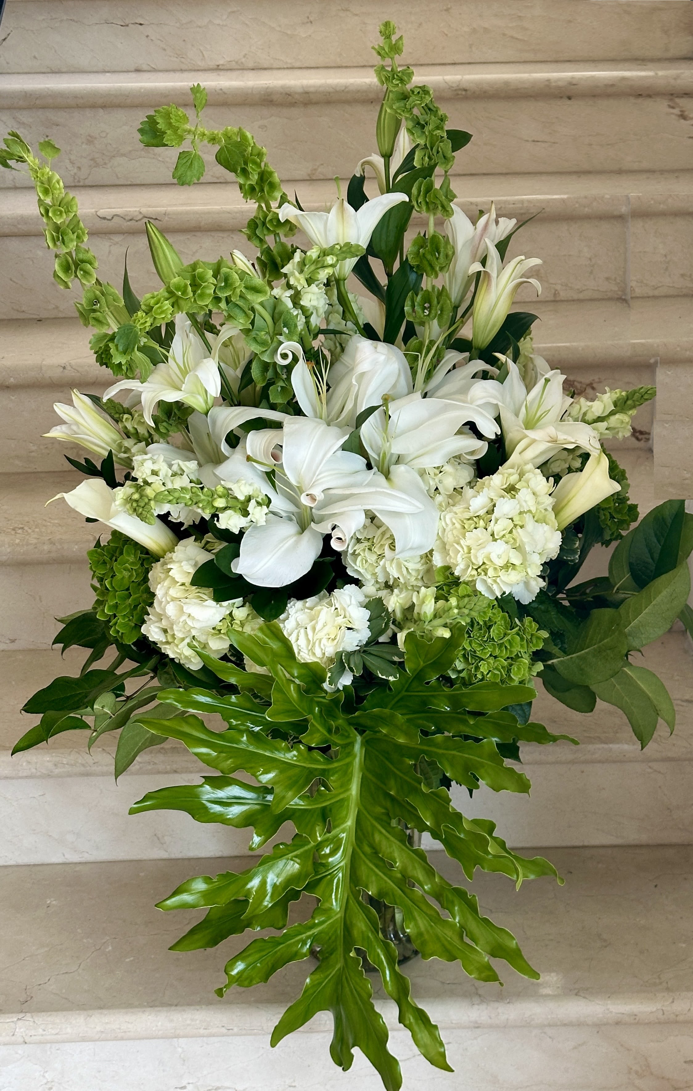 Grand Floral Arranged with Premium Flowers and Premium Vase - An all white extra large flower arrangement with white roses, white lilies, hydrangeas and calla lilies, arranged with greenery in a vase. Approx. 36 inches tall by 24 inches wide.