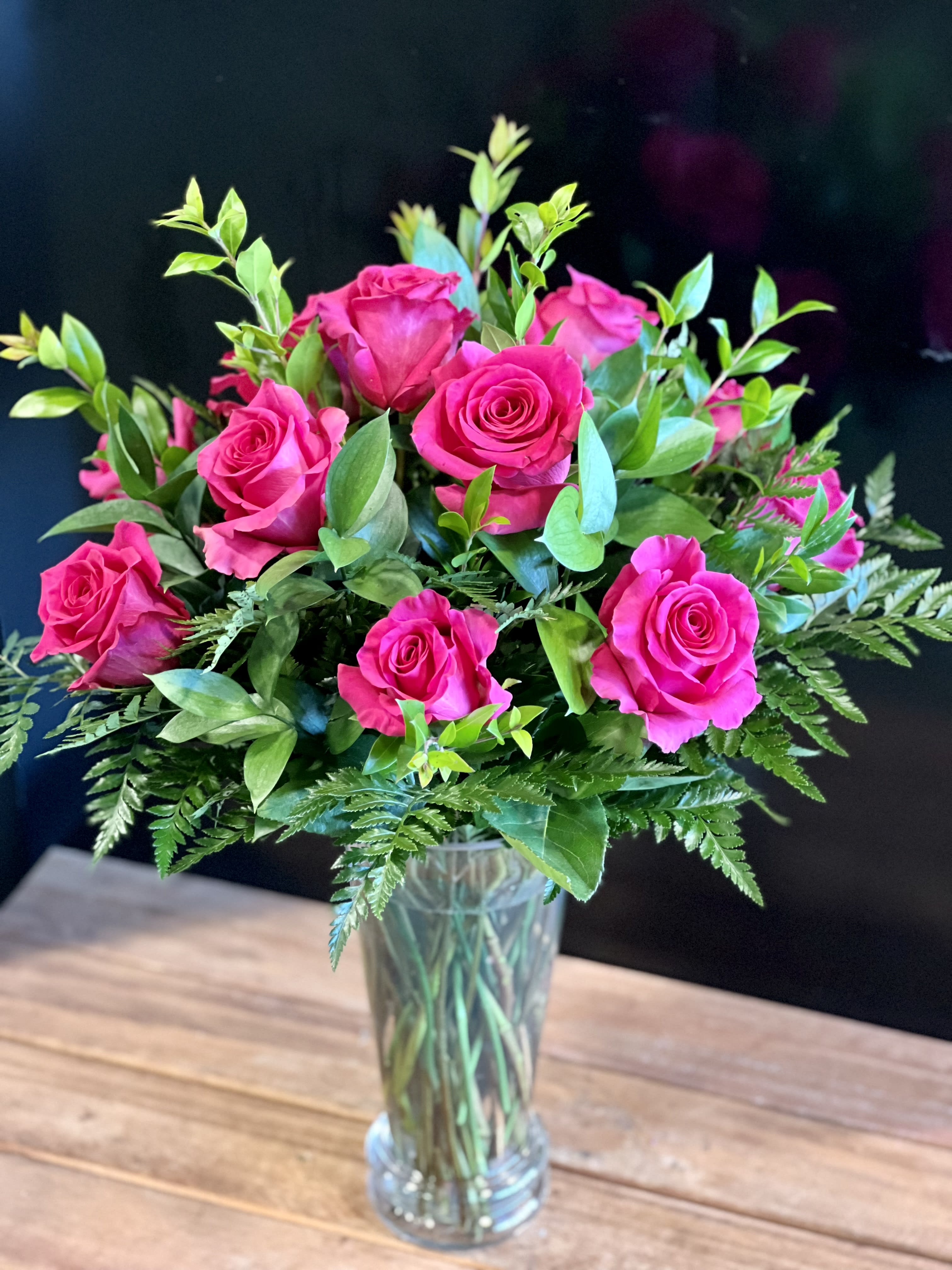 Traditional Dozen in Hot Pink - Show someone how much you care with a dozen hot pink roses! Premium long stemmed roses are designed beautifully with lush greens. Upgrade to 24 or 36 roses to really spoil them!  Vase height is 10.5 inches.