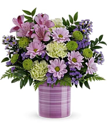Teleflora's Sweet Swirls Bouquet - Pretty as can be in a hand-painted ceramic keepsake vase that swirls with shades of purple, this luxurious lavender bouquet will surely make mom's day! This lovely bouquet includes lavender alstroemeria, green carnations, large lavender monte cassino asters, lavender daisy spray chrysanthemums, green button spray chrysanthemums, lavender sinuata statice, huckleberry and leatherleaf fern. Delivered in a Serene Swirl vase.