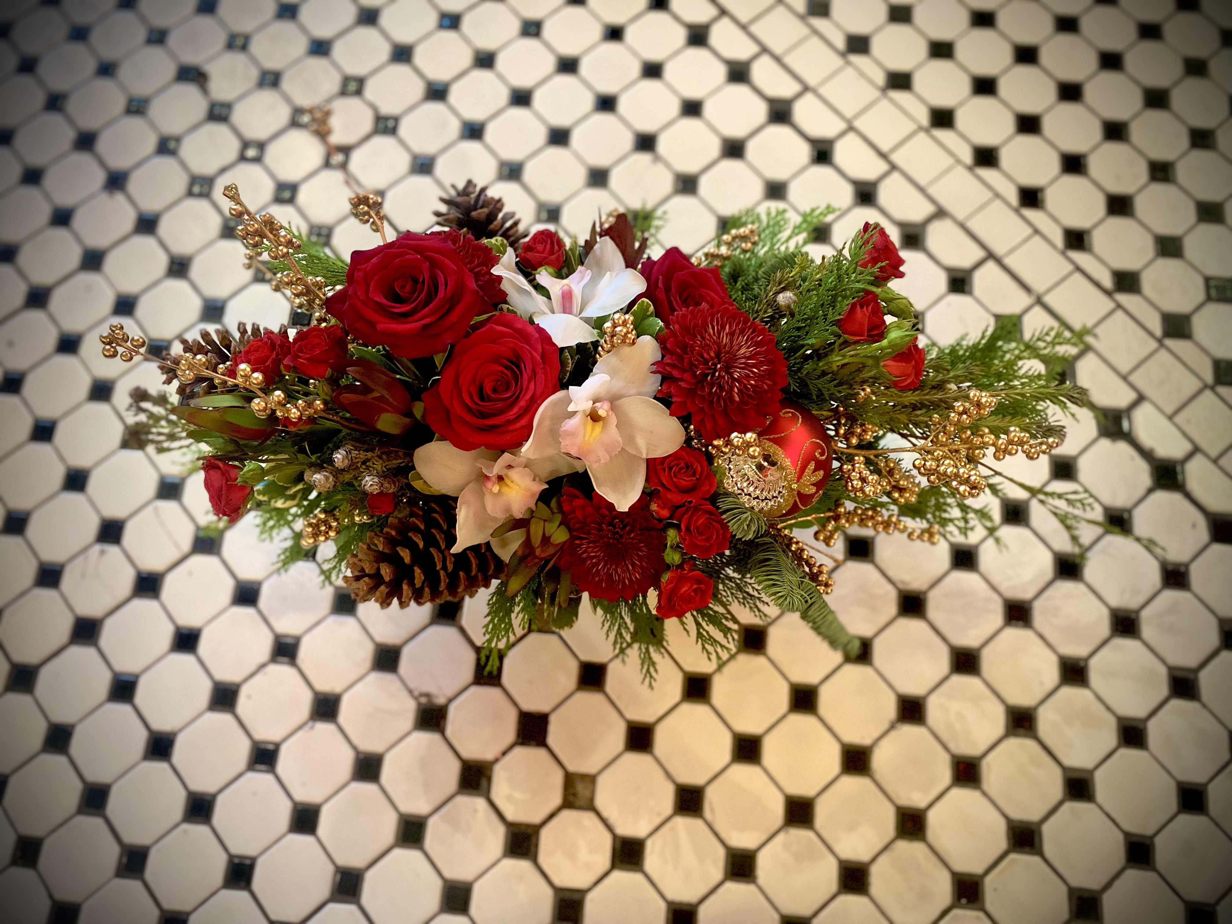 Regal Holiday  - This regal centerpiece promises to bring just the right amount of opulence to your holiday table. Featuring our premium white orchids, red roses, and mums along with pine cones, berries and a keepsake ornament,  arranged in a gold compote with an assortment of Noble Fir and Port Orford Cedar.  Approximately 23 inches long and 13 inches tall perfect for any home or office space. 