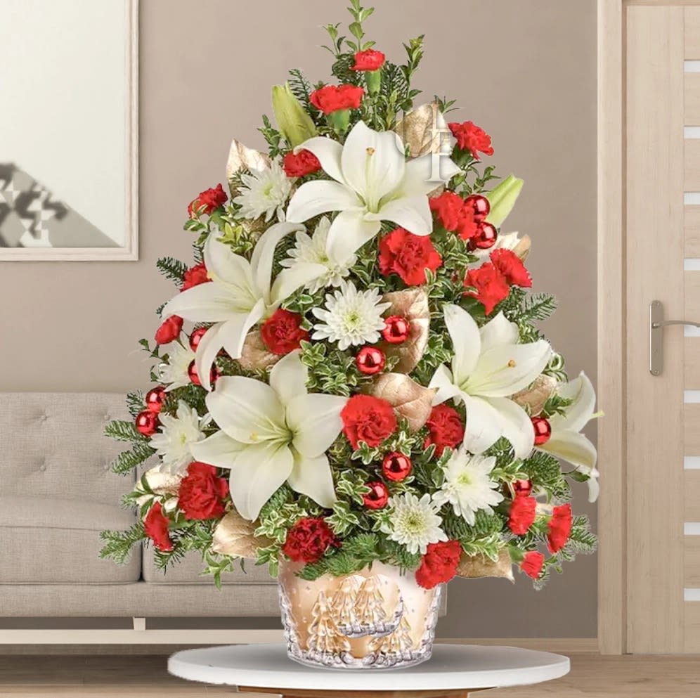 Enchanting Christmas Tree  - Illuminate the holiday spirit with our enchanting Christmas tree-inspired arrangement. Crafted with care, it boasts white lilies, red carnations, and white chrysanthemums, accentuated by golden sprayed leaves and vibrant red Christmas balls. the perfect centerpiece for festive gatherings or a heartfelt gift to spread joy and warmth during the holiday season.