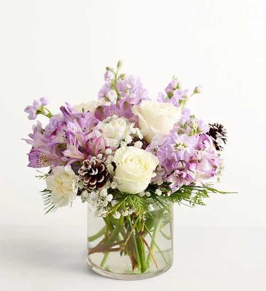 Lovely Lavender for Winter - We’ve captured the peaceful beauty of winter in our lovely bouquet. A seasonal version of our best seller, it’s loosely gathered with soothing lavender &amp; white blooms, cascading greenery all around and pinecone accents for a rustic touch. A truly wonderful way to express your sentiments this time of year.